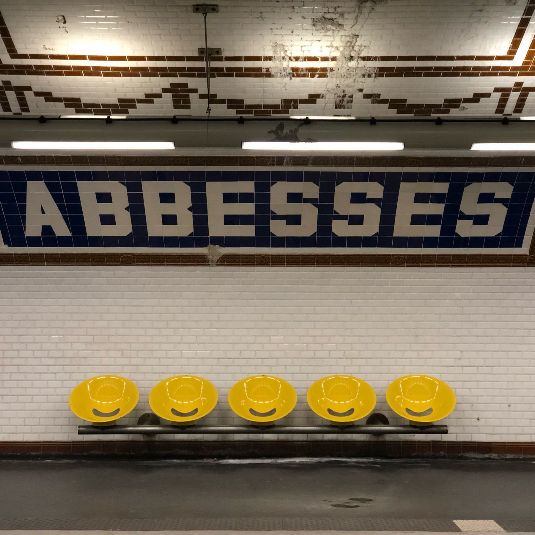 Subway station wall with tile “Abbesses” lettering.