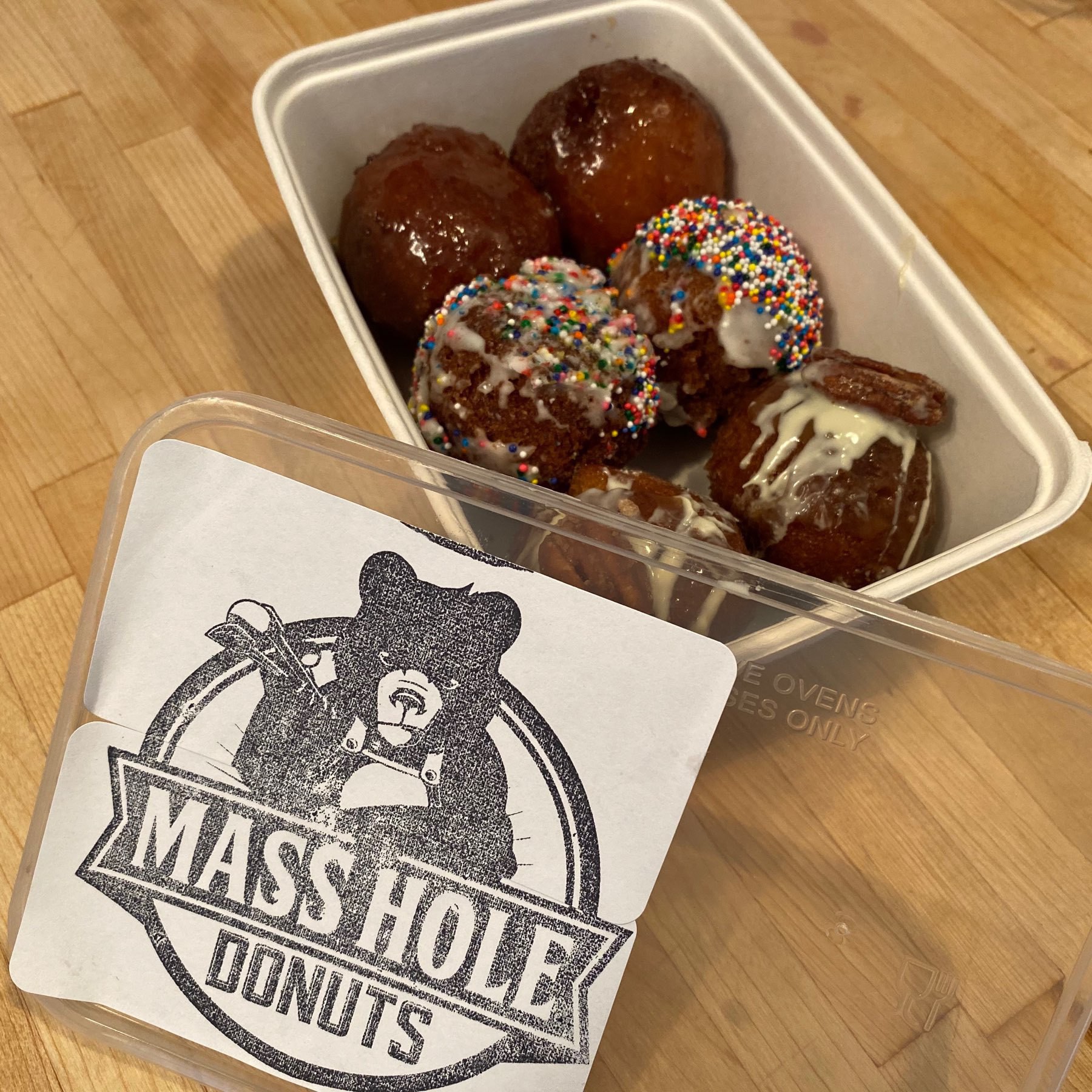 Six decorative donut holes in a box labeled "Mass Hole Donuts."