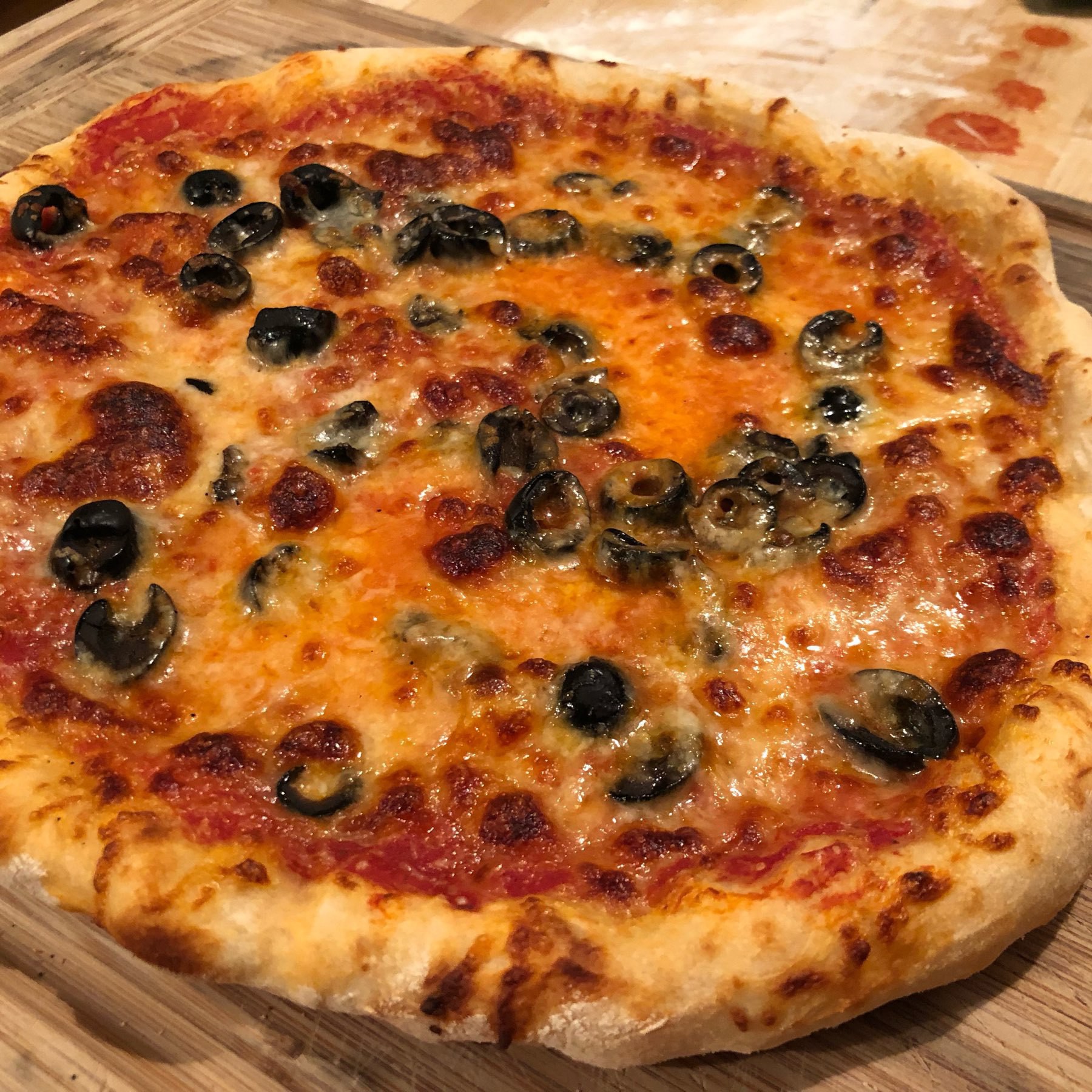 Homemade pizza with cheese and black olives.