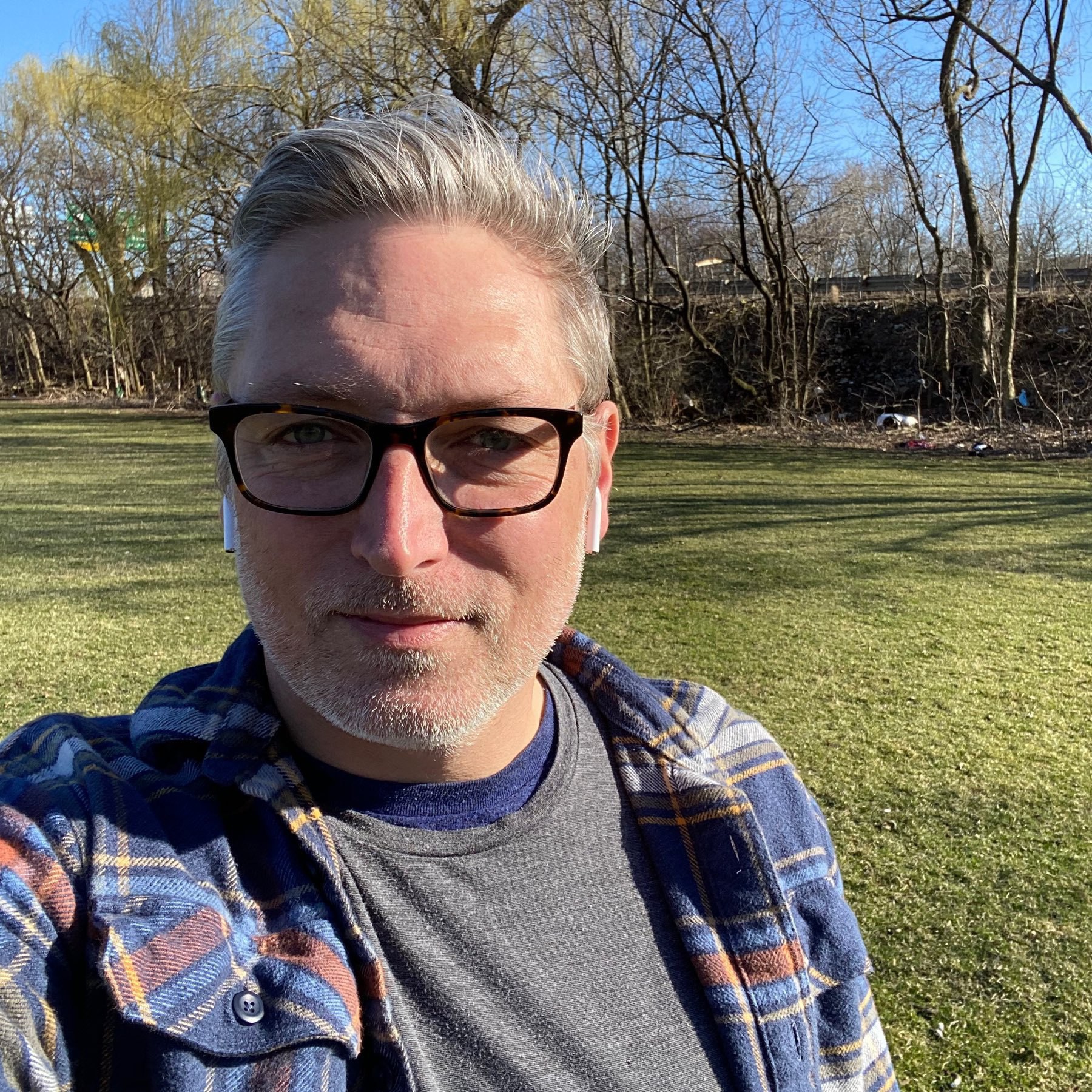 Self portrait against backdrop of green grass and trees.