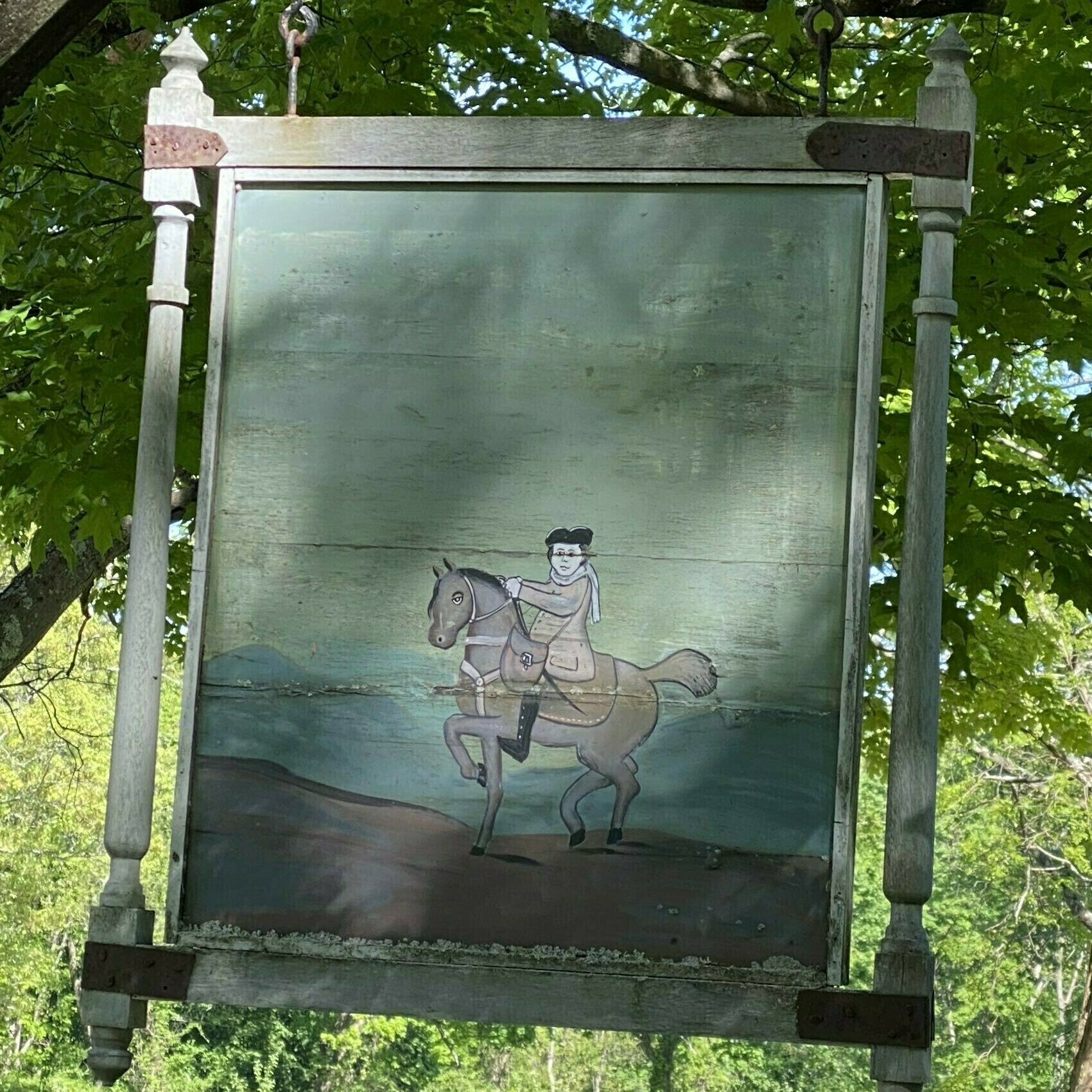 sign featuring a painted illustration of a man on a horse