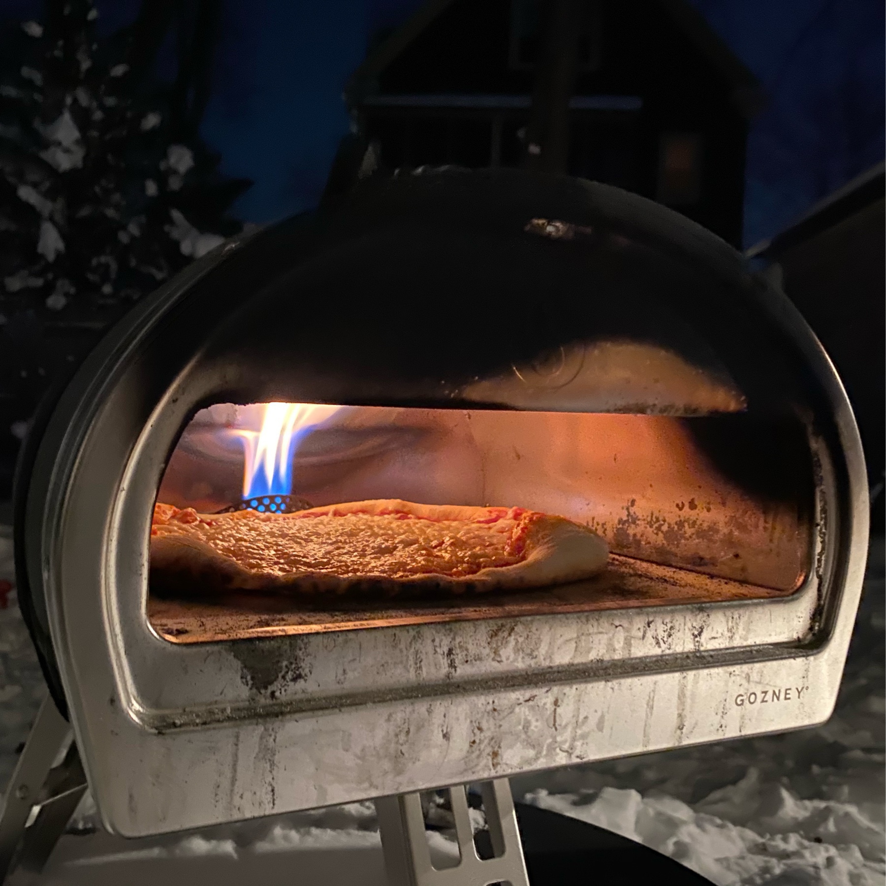 picture of a pizza oven with flame glaring against a backdrop of snow