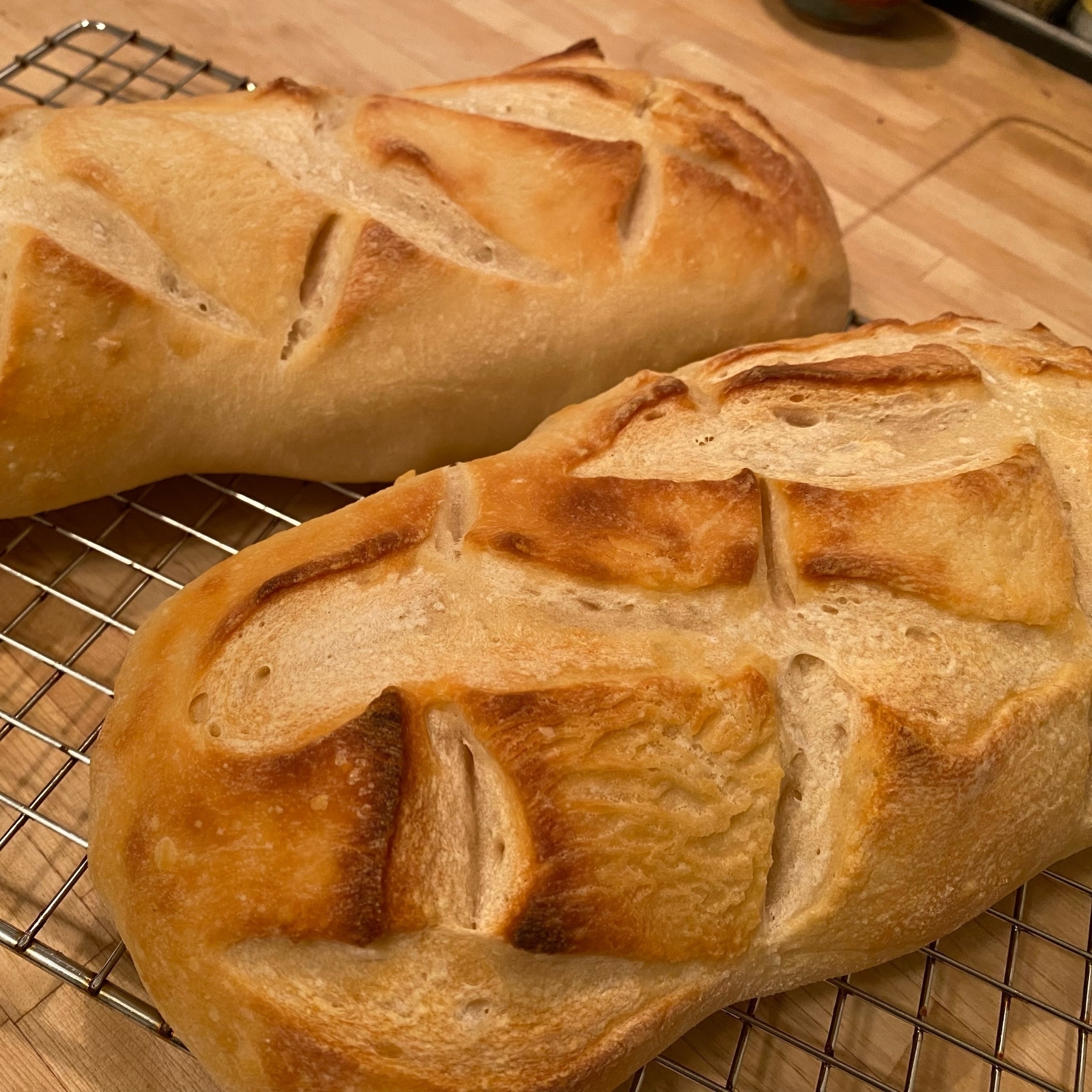 picture of two loa es of freshly baked bread with criss-cross slash patterns on top