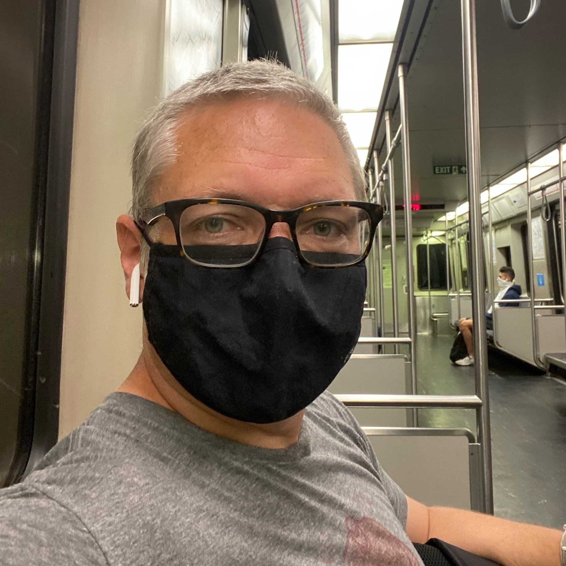 selfie wearing a black facemask on an almost empty subway car