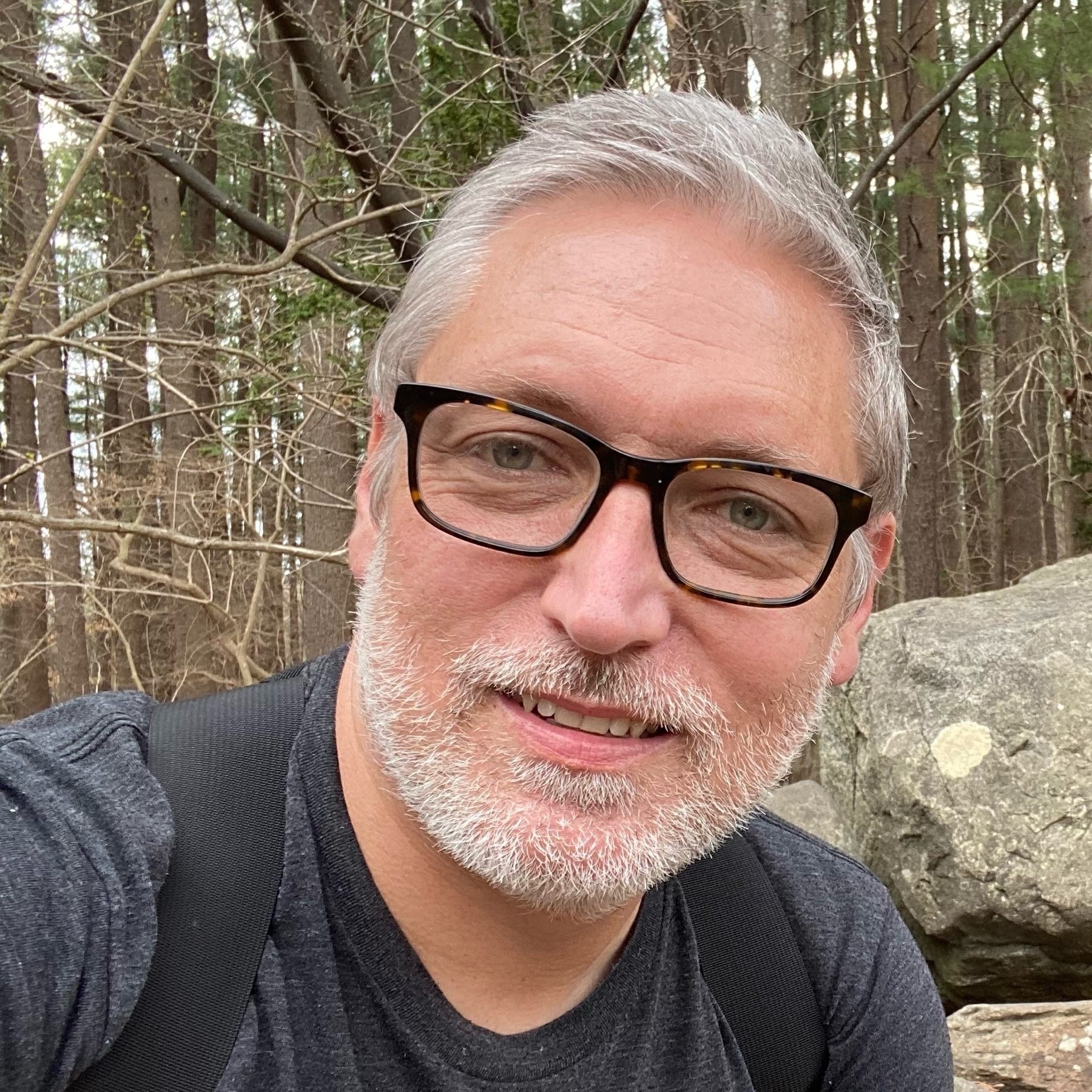 self portrait in the woods with head tilted sporting white beard stubble and gray hair