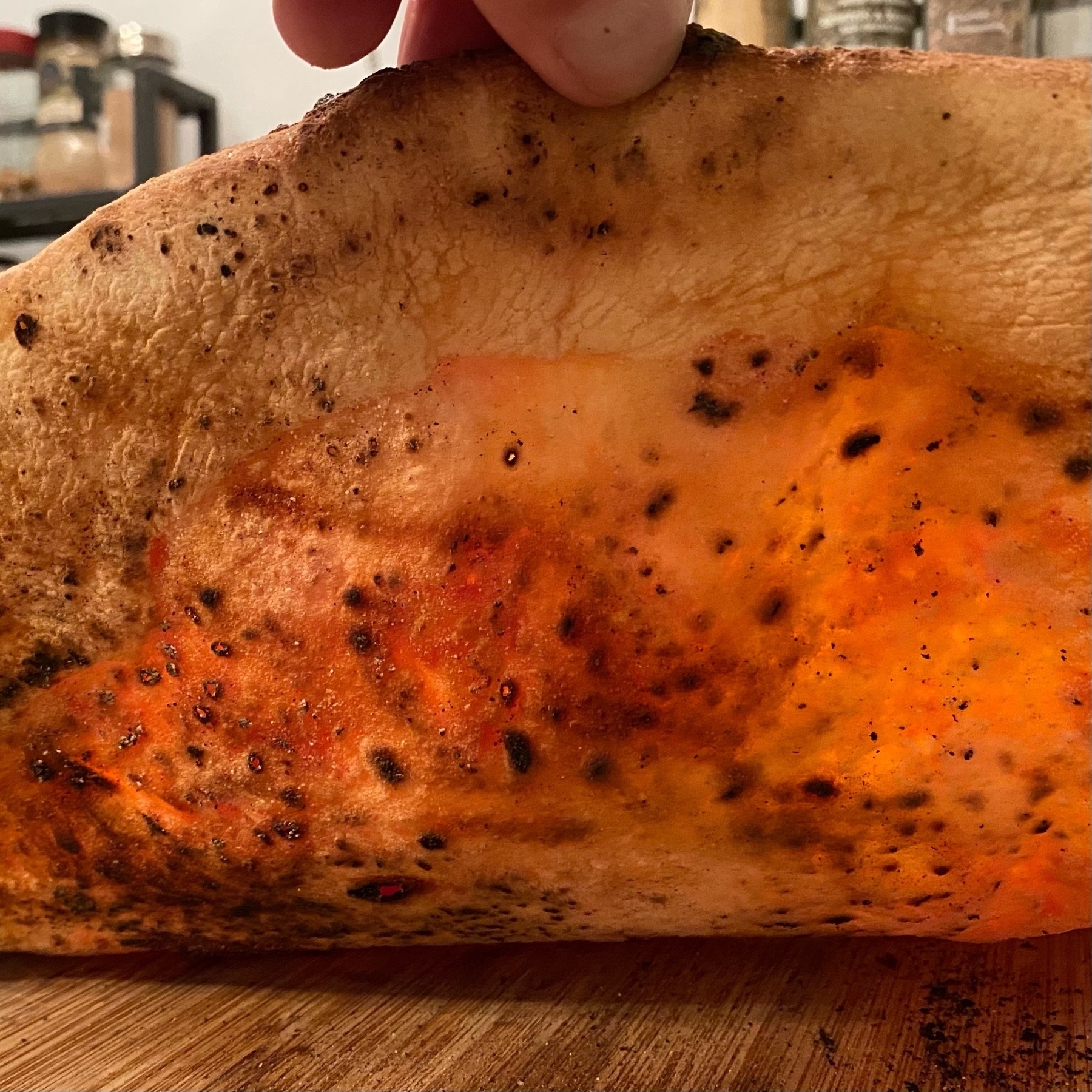 picture of a bottom of a cooked pizza with light shining through a thin crust