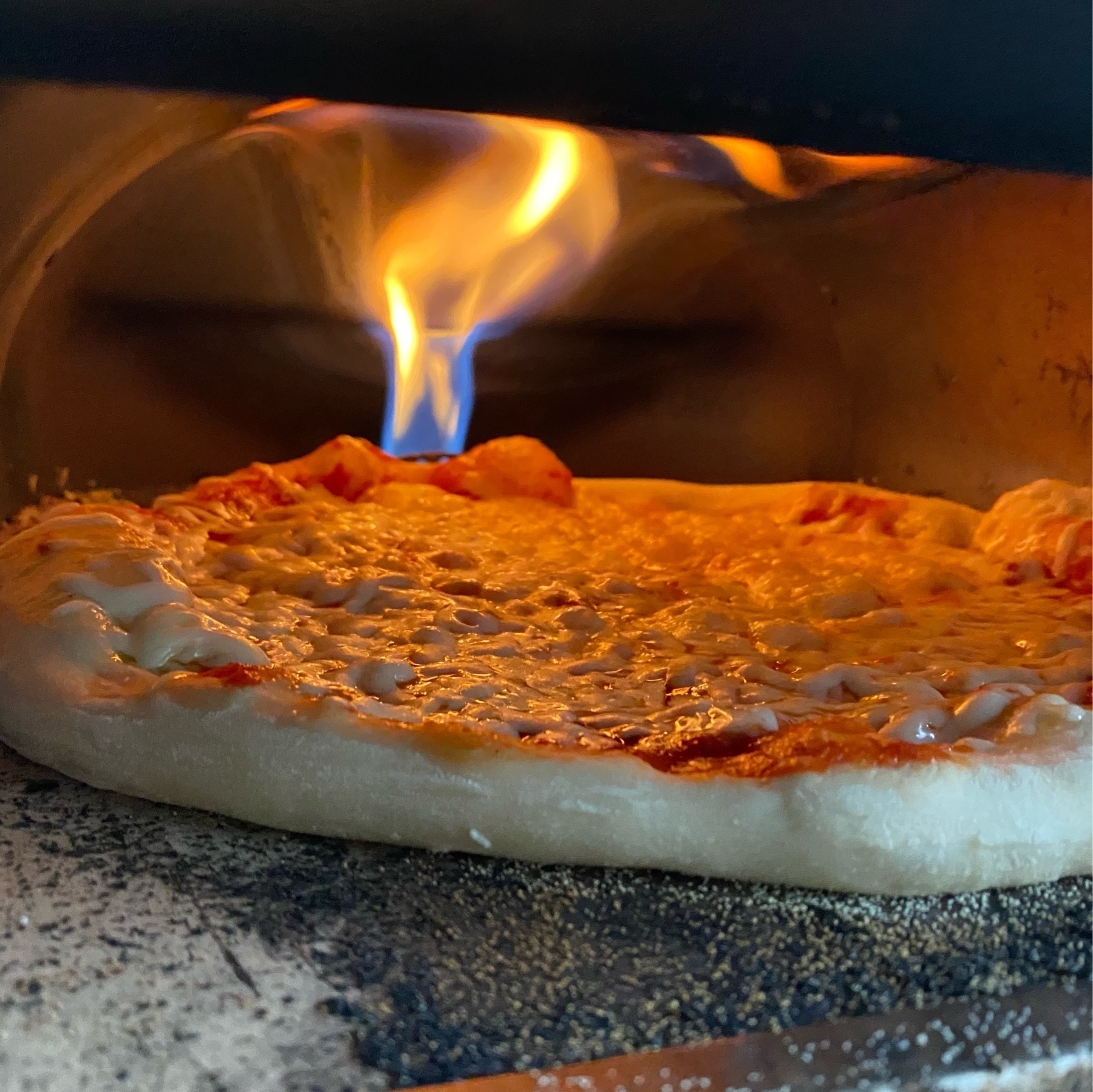 picture of a pizza baking in an oven with prominent flame