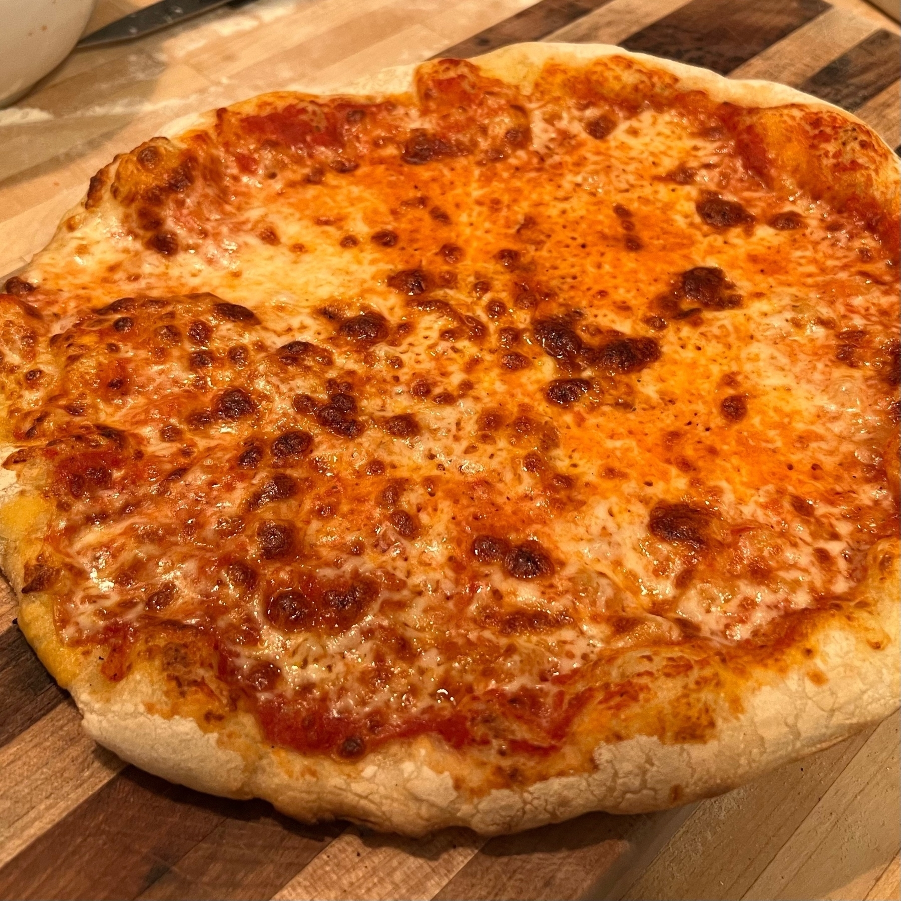 a fresh-baked cheese pizza on a wooden slab