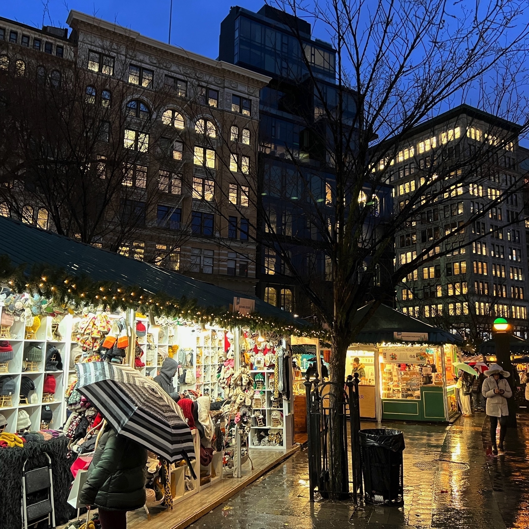 Temporary holiday market stands constructed in Union Square Park with a backdrop of buildings surrounding the park.