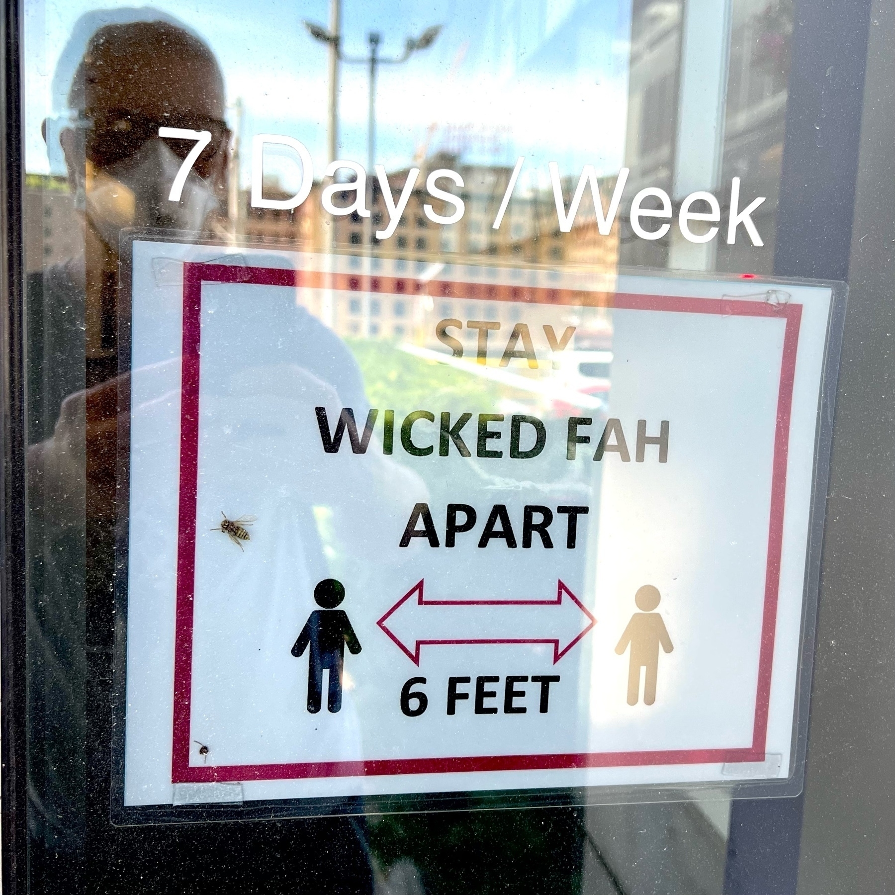 placard in a window reading "stay wicked fah apart" with a depiction of two human figures distanced.