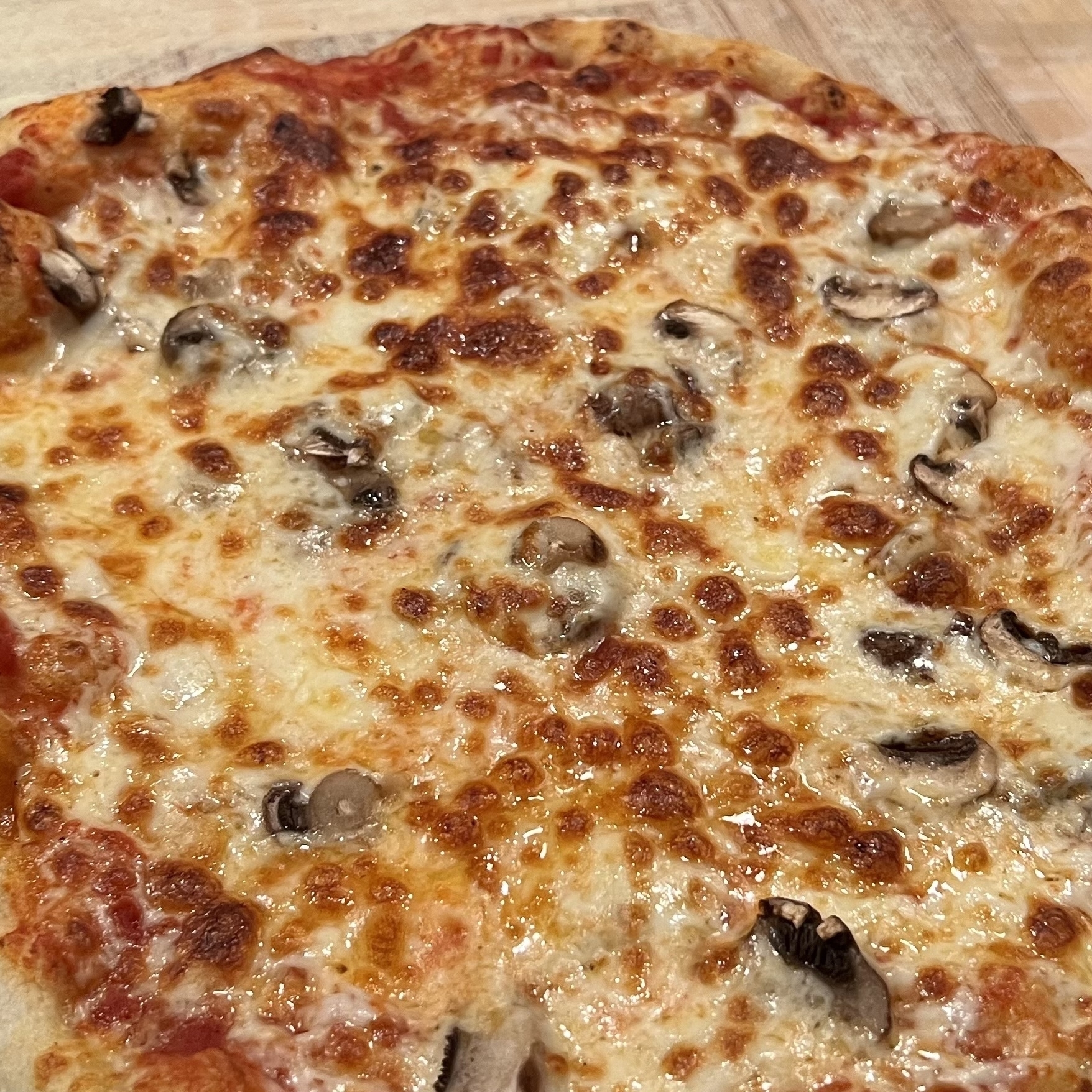 picture of a freshly baked hinemade pizza with tomato sauce, cheese, and mushrooms