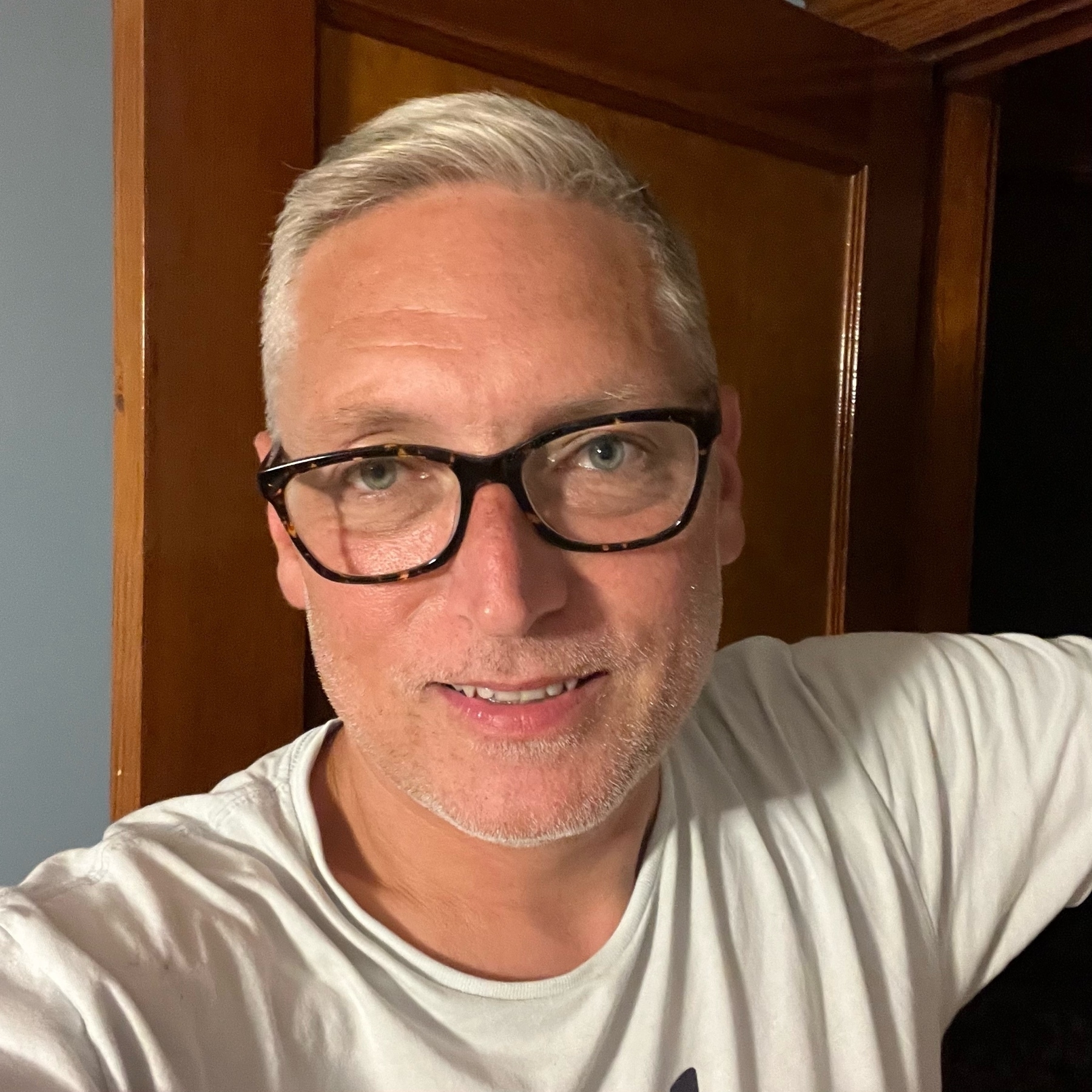 Selfie of me, a Caucasian 48 year old man with short gray hair, glasses, and a light blue t-shirt