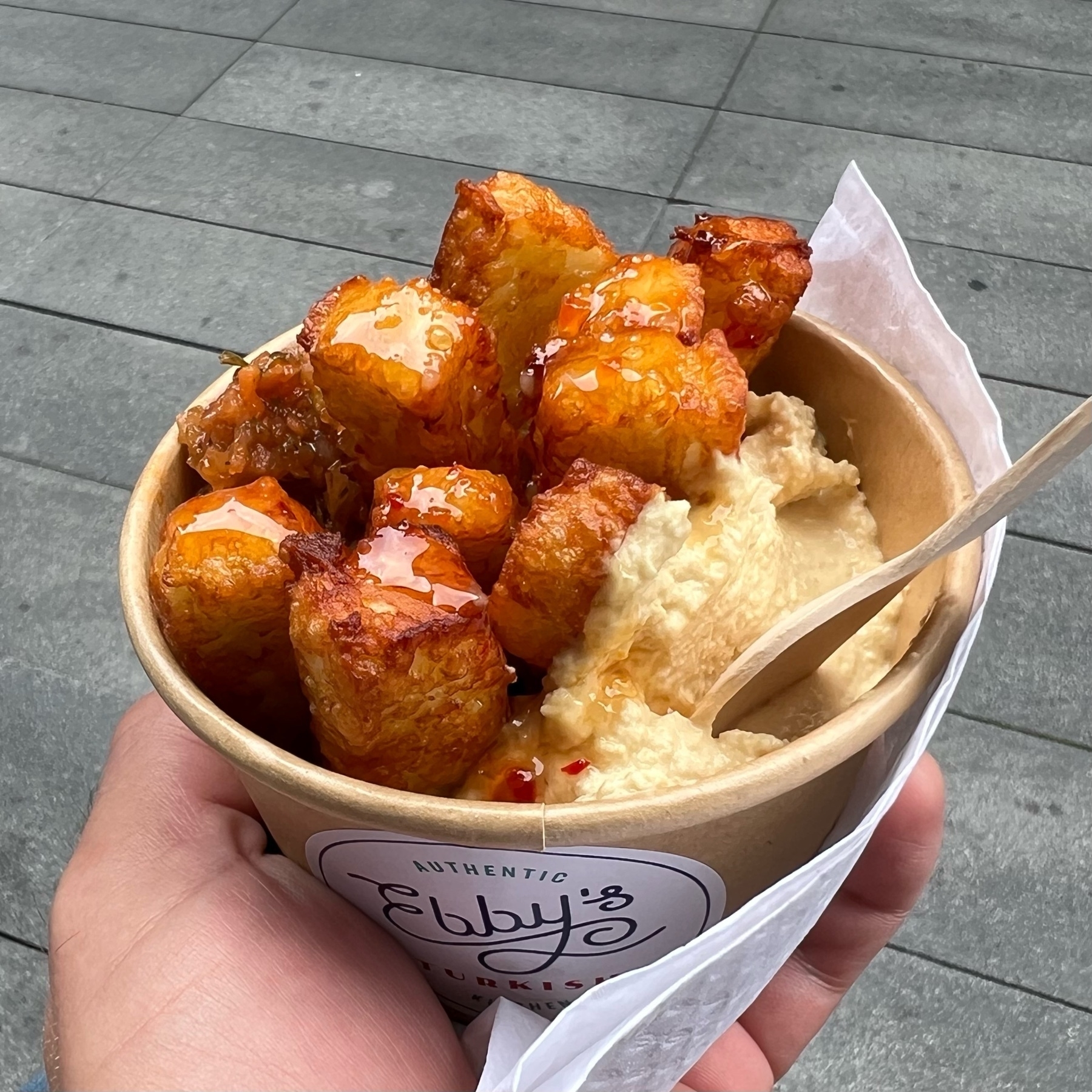 Cardboard cup filled with fried halloumi cheese with a side of hummus