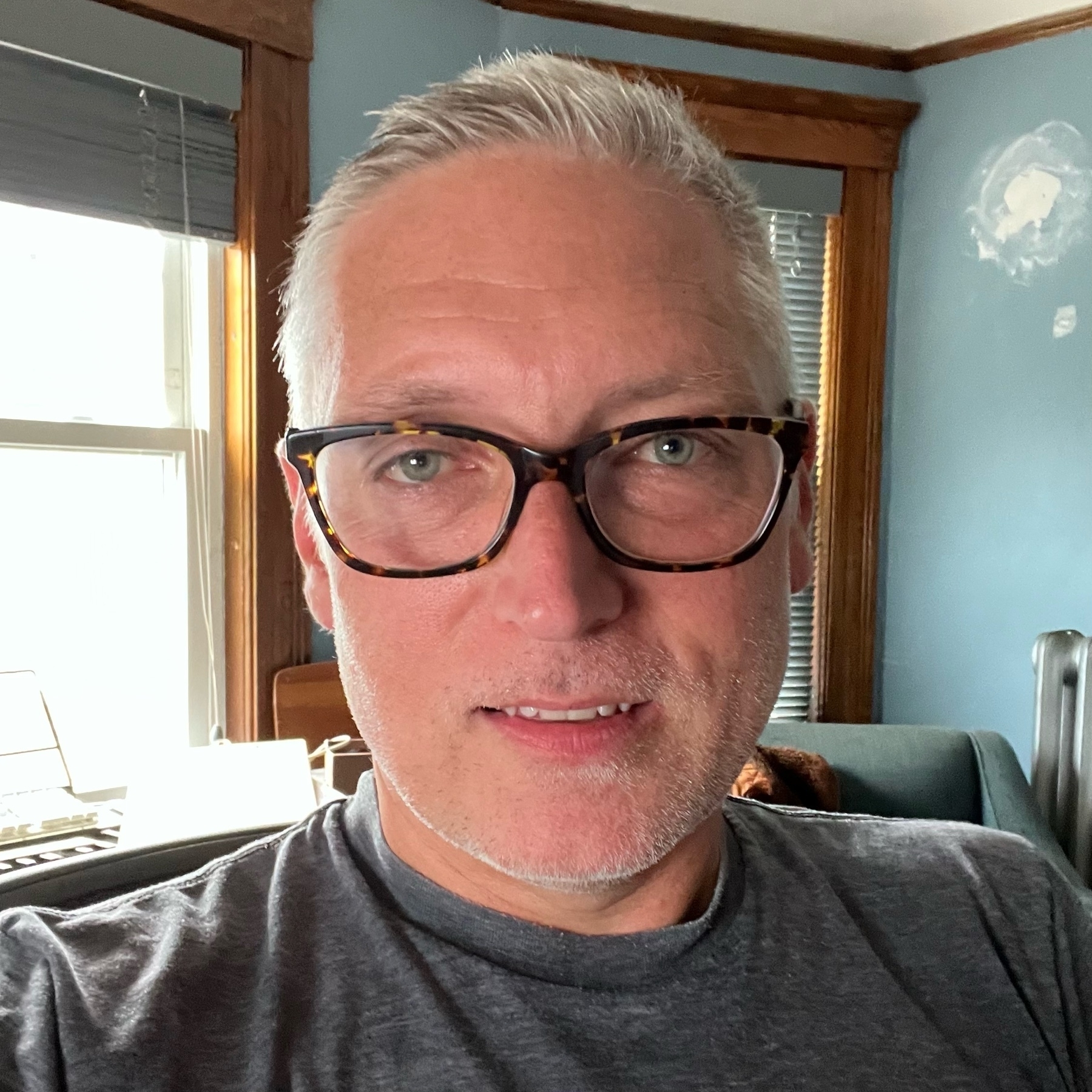 caucasian man with grey hair and glasses in a casual T-shirt