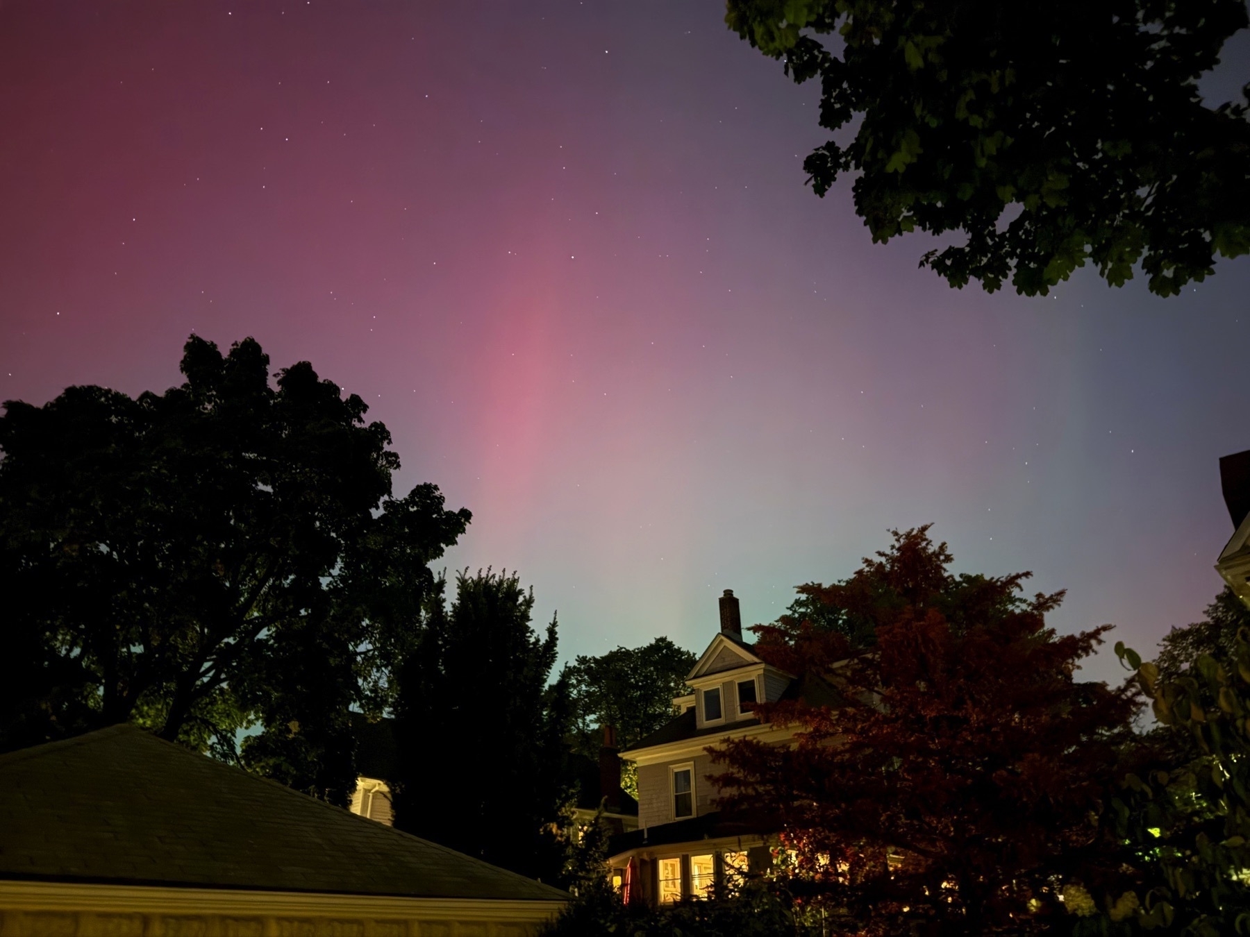 Picture of a night sky with exaggerated colors of pink and blue, due to the northern lights phenomenon.