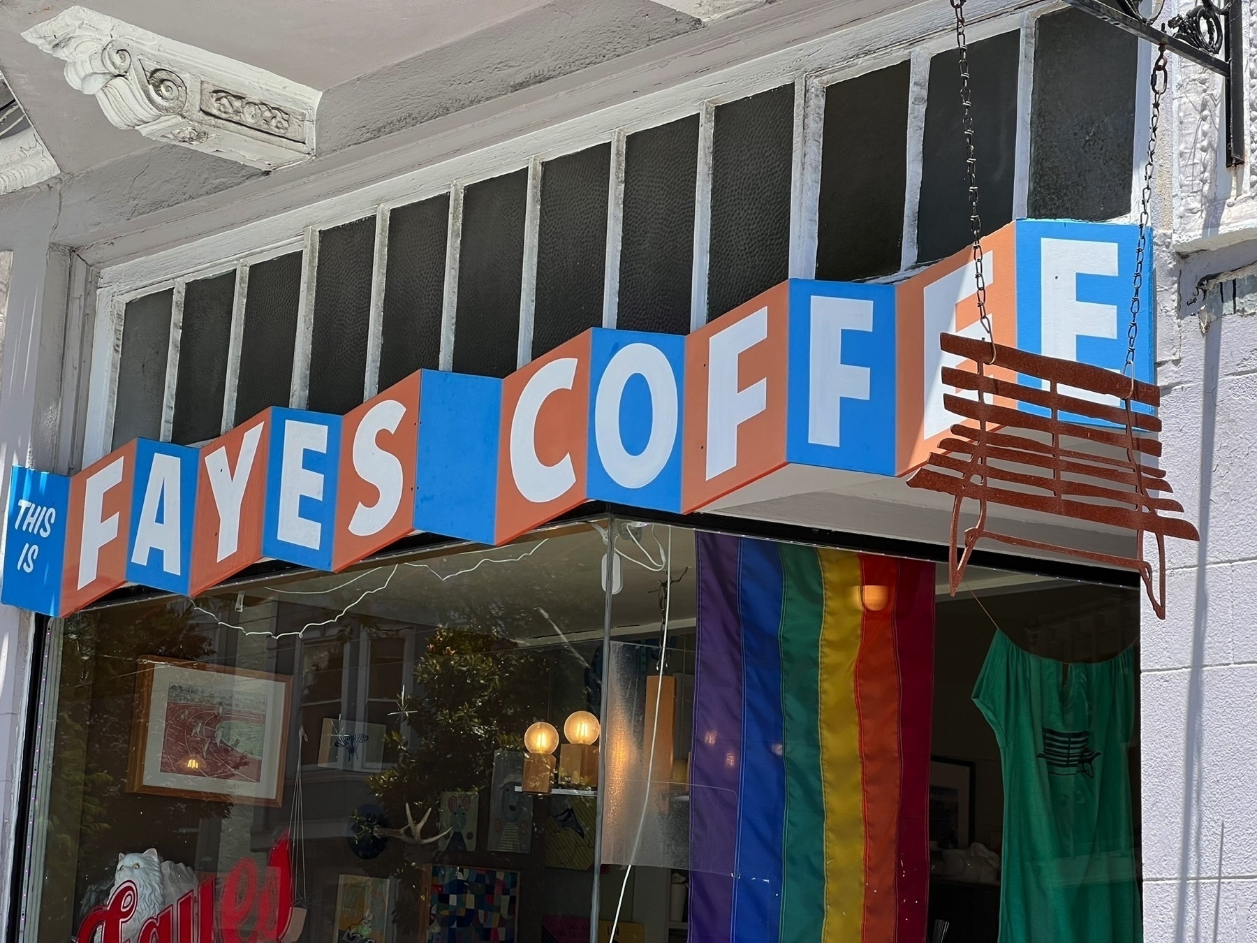 Exterior view of FAYES COFFEE with a colorful, alternating red/blue accordion style sign.