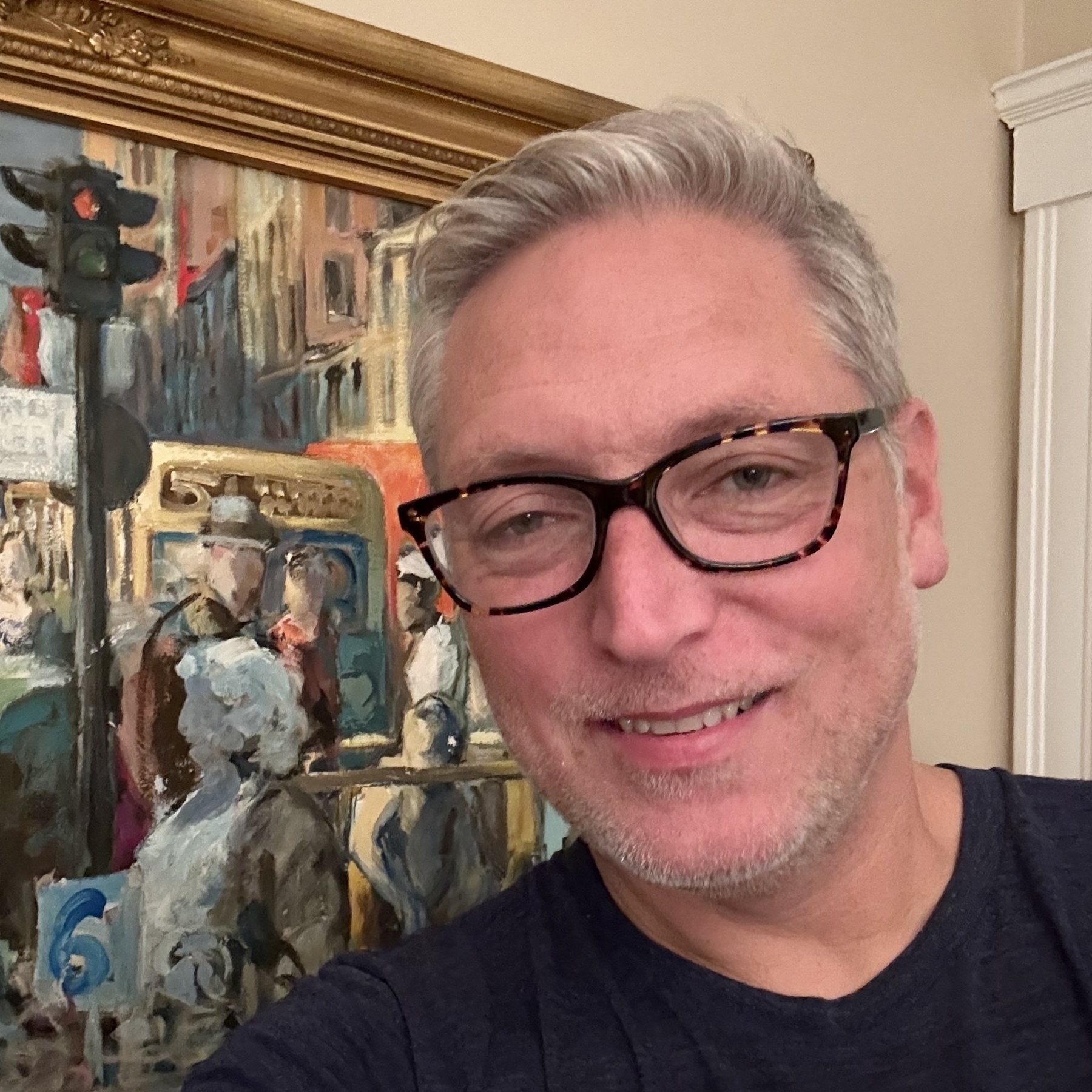 Caucasian man with grey hair and grey stubble smiling into the camera