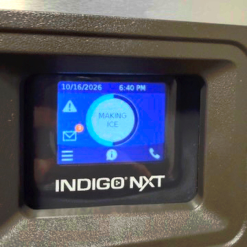 Picture of an interactive screen on an industrial ice maker, showing a brand name "INDIGO NXT" and an infographic menu with a "3" badge over the email icon.