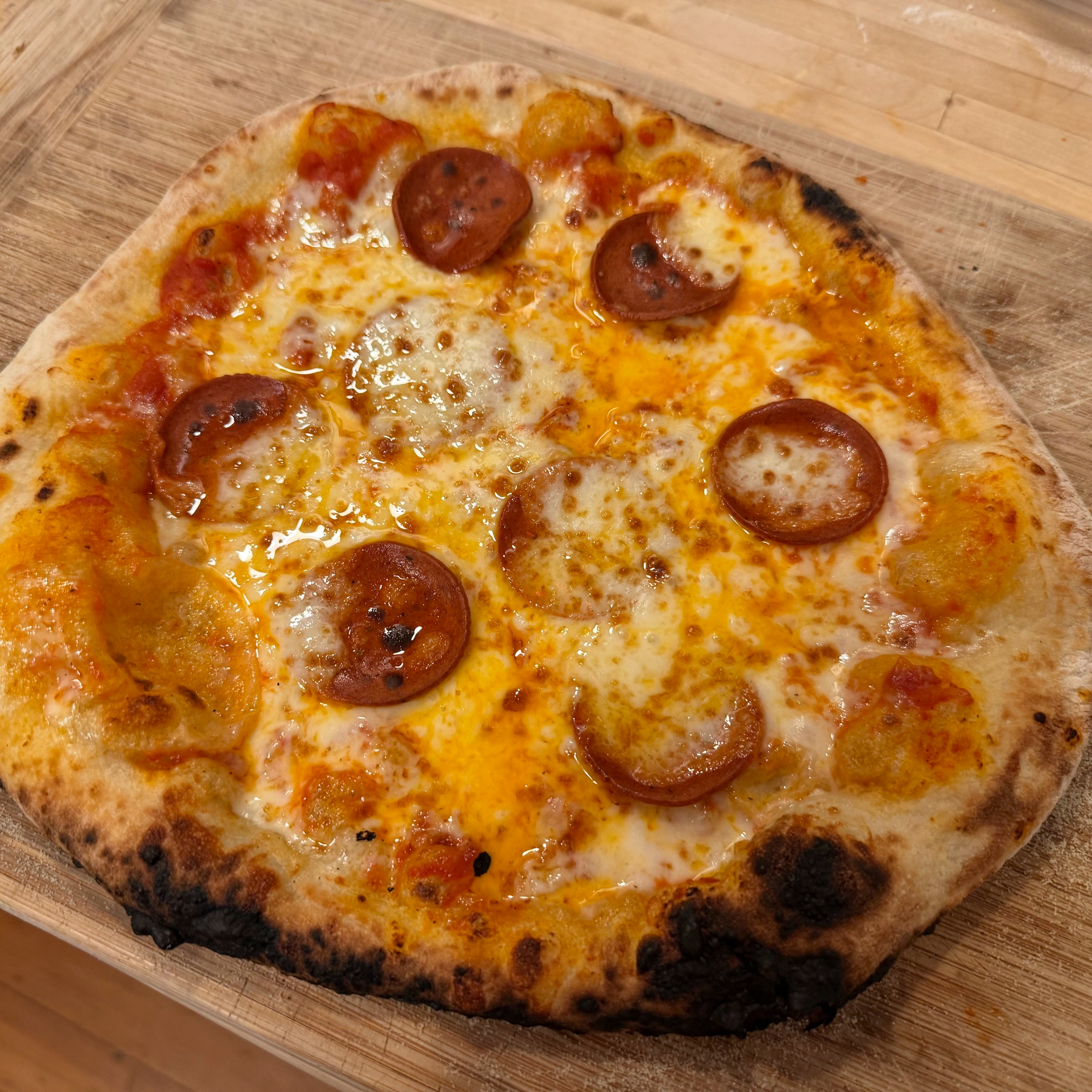 Home baked plant-based pepperoni and dairy cheese pizza with puffy, charred crust.