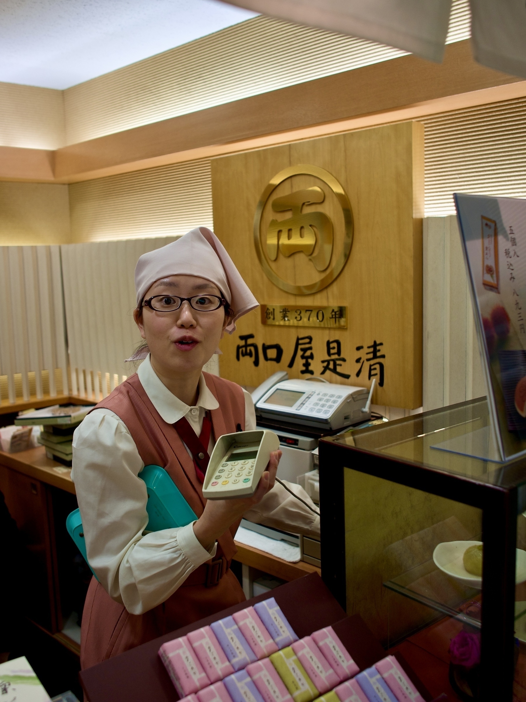 Clerk in salmon pink uniform at Japanese sweets shop handing me a credit card scanner. 