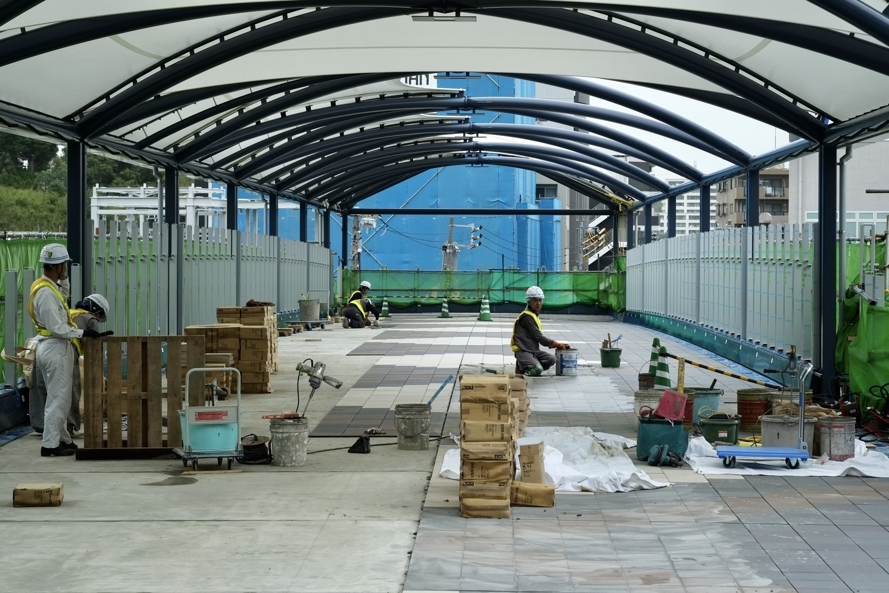 Construction workers finishing up the tiles on a footbridge across the tracks at JR Totsuka, Yokohama, Japan. 