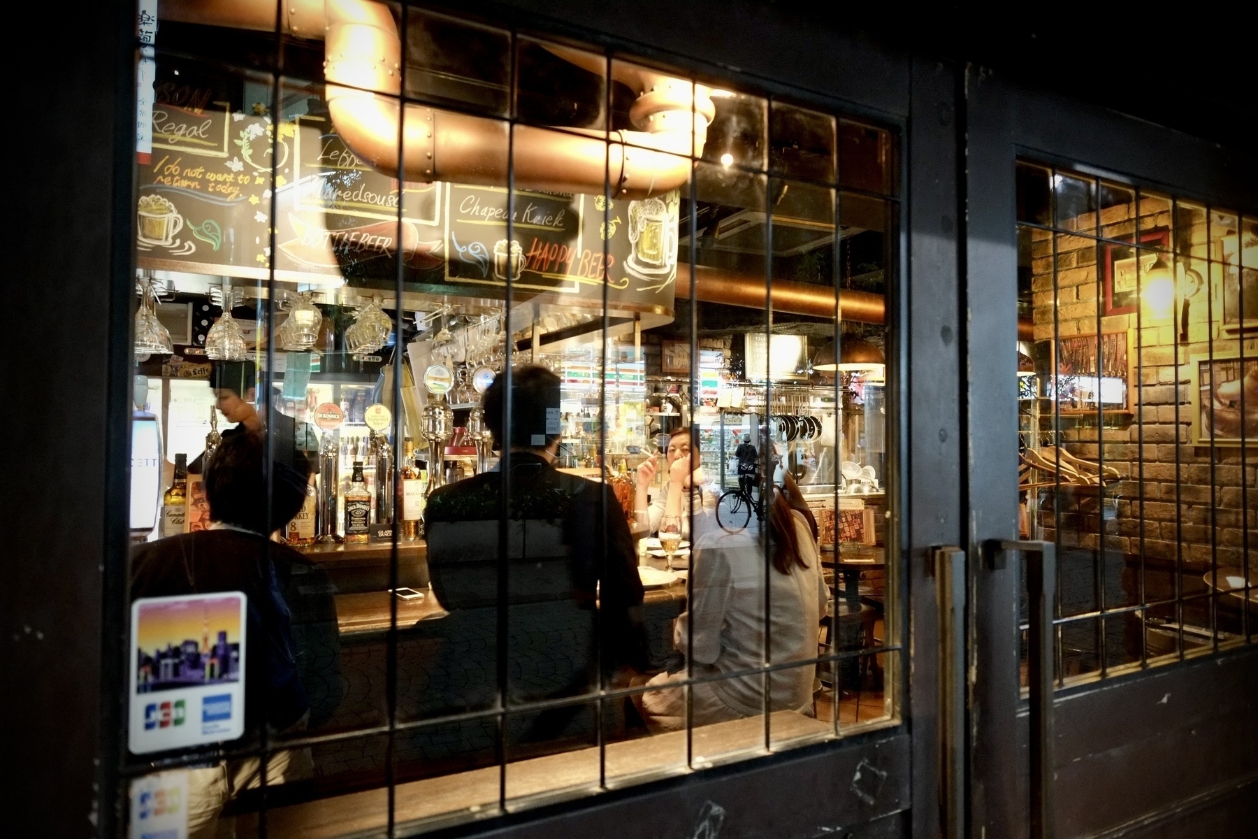 Patrons at a bar in Shinagawa Tokyo at night, with one looking directly at the camera. 