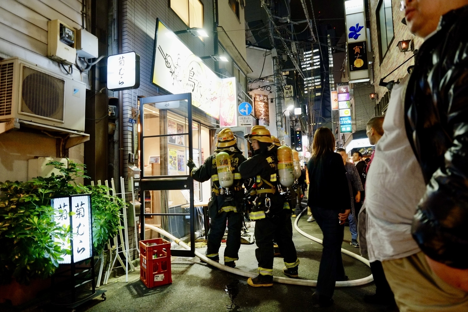 Fire fighters entering a blaze site in the narrow back street area of Shimbashi Tokyo, Japan. 
