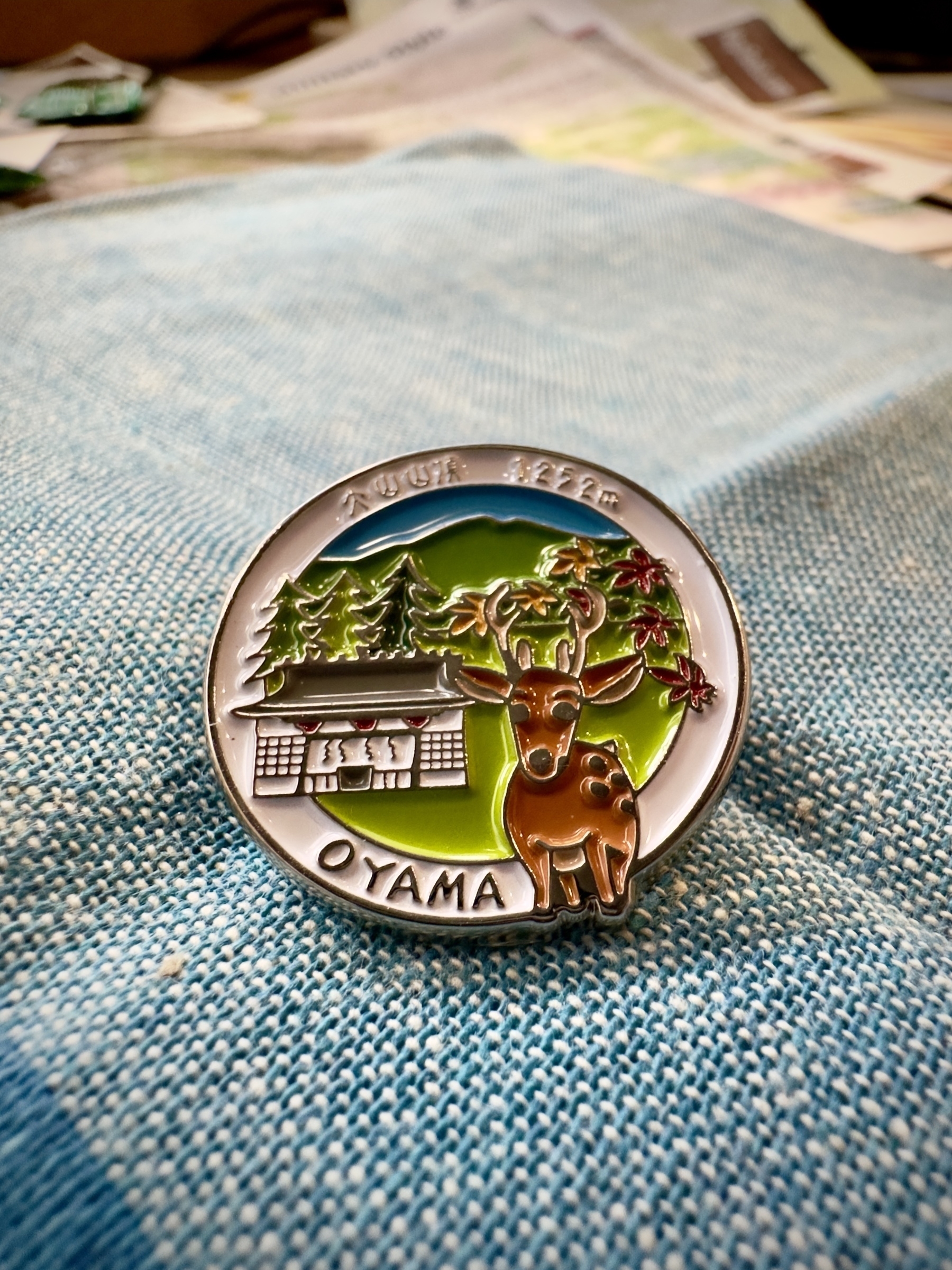 Pin badge from Mt. Oyama shop, showing elevation and the name in Japanese and English, depicting a shrine and deer in a forest scene.