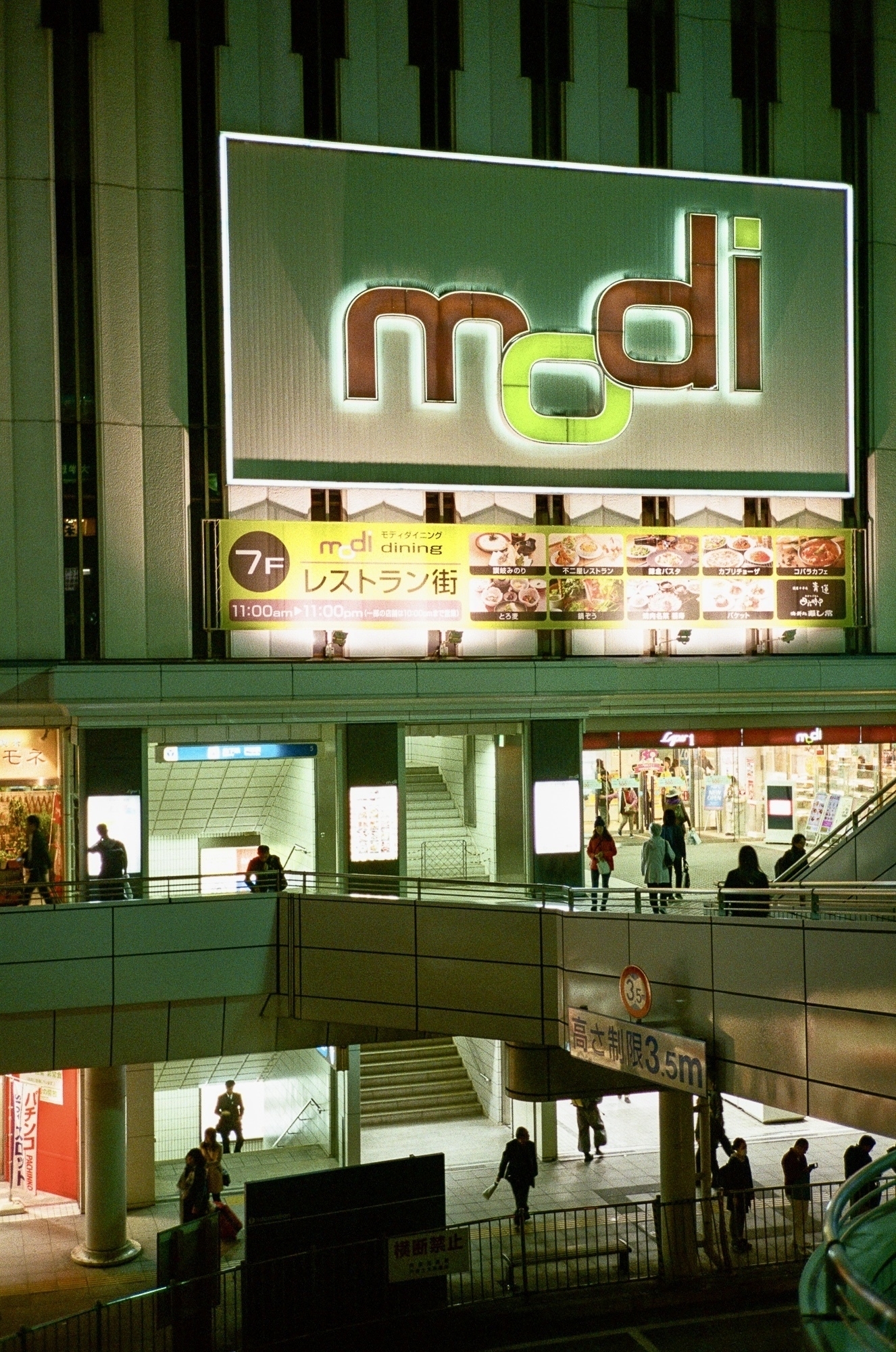 Night view of the “Modi” shopping center building, showing ground and 2F levels, taken from the platform plaza outside Totsuka station.
