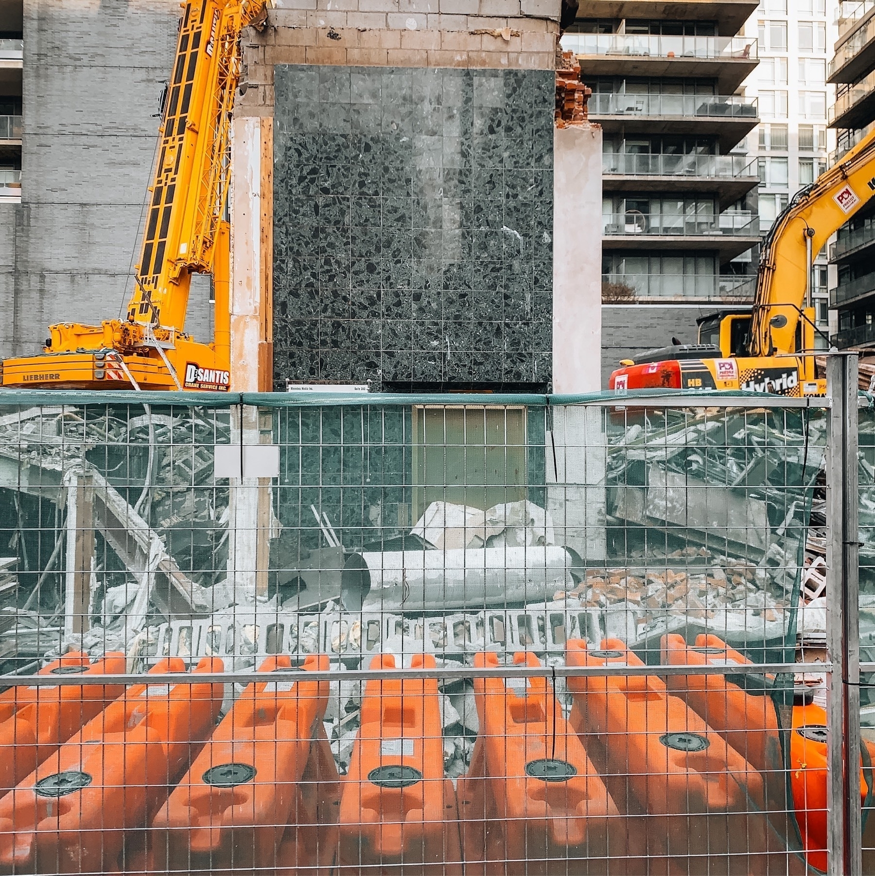 A construction site on the northeast side of Bathurst St and King St West, where they are tearing down a building a subway station for the Ontario Line. The only thing that is left is the first floor elevator, which looks like a marble box with a brass door.