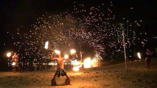 A Fijian firedancer with sparks flying in the background