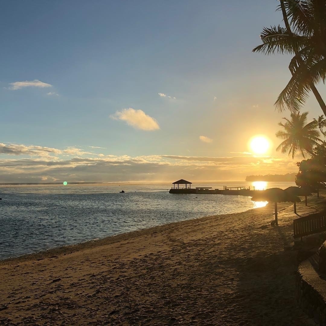 Sunset over a beach in Fiji, with palm trees swaying in the breeze