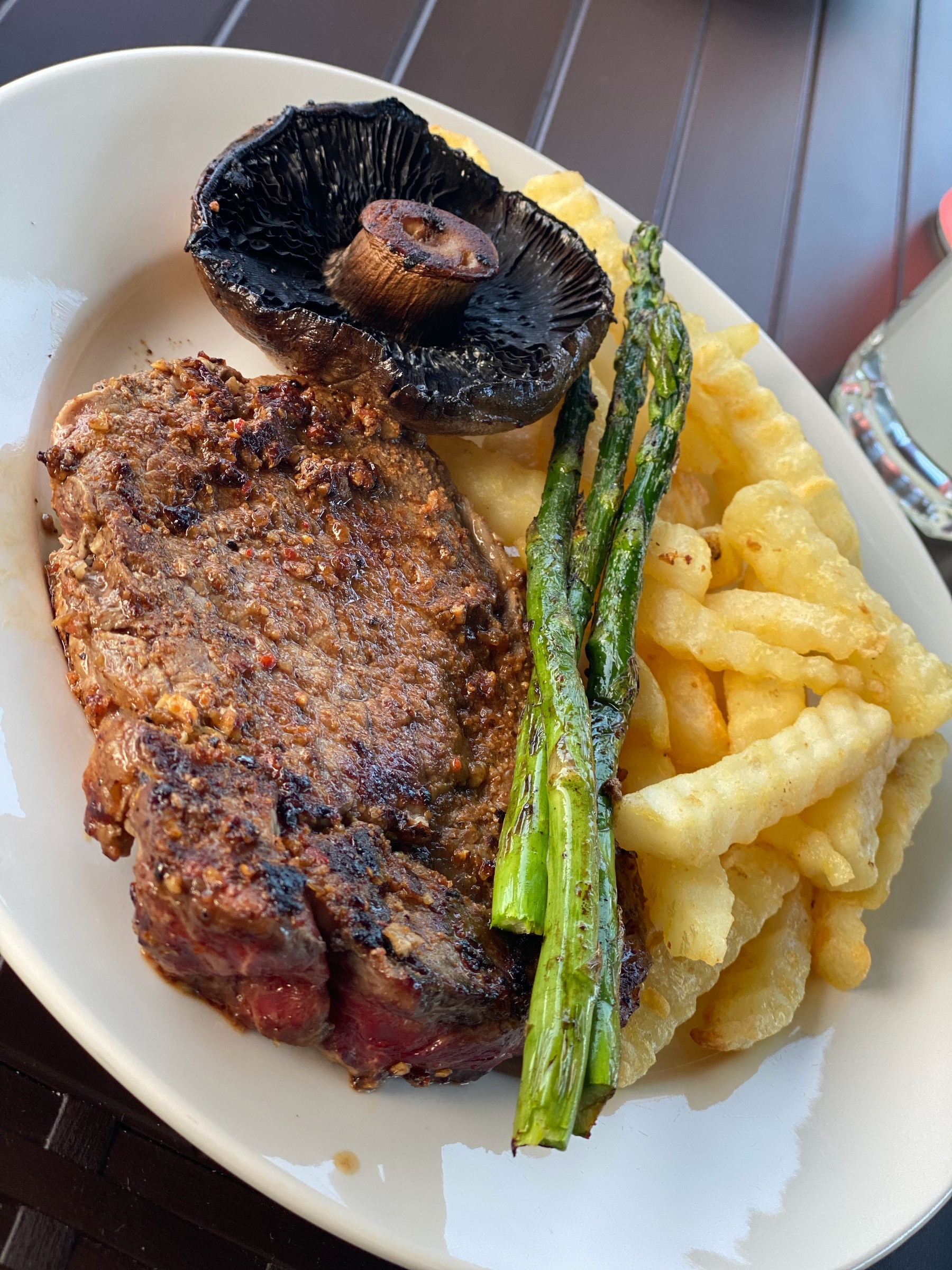 Steak, mushrooms, chips and asparagus on a plate. It was tasty