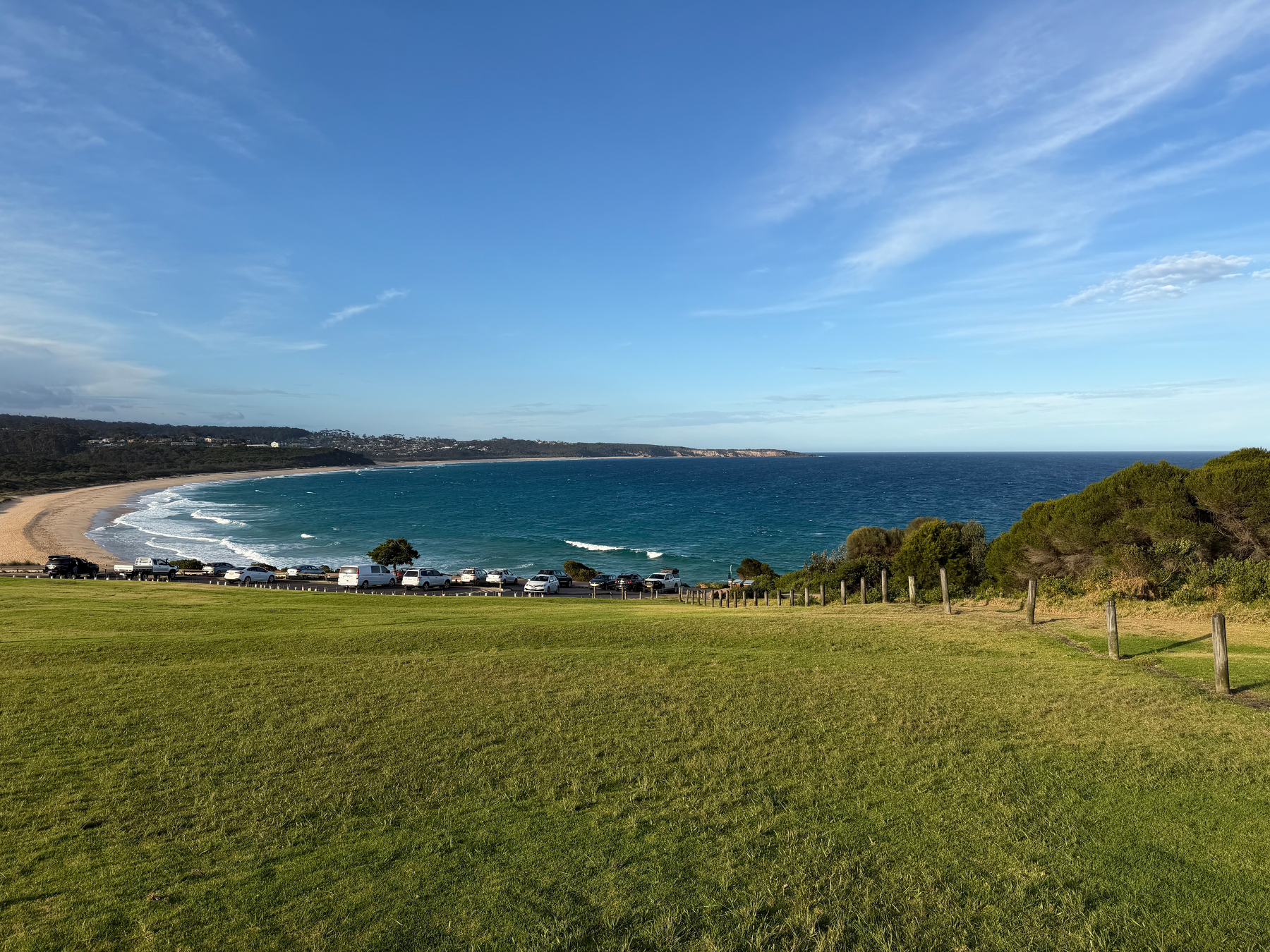 View of a grassy slope leading to waves crashing on a beach