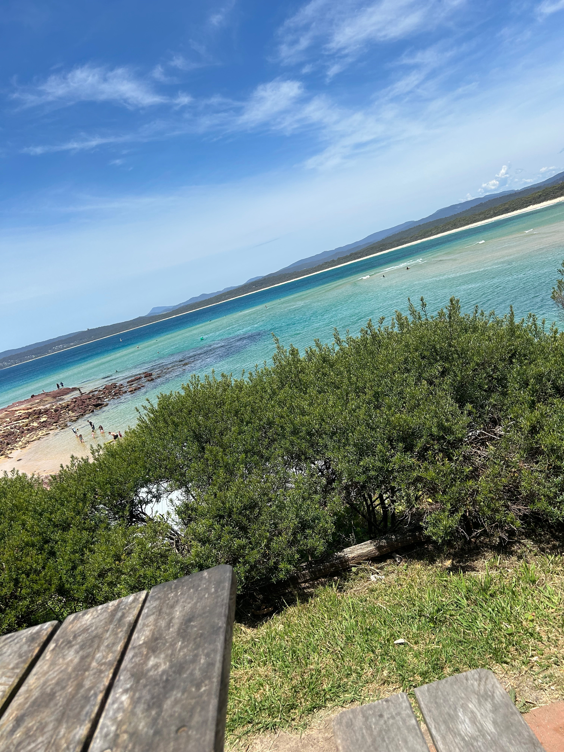 An angled view of a beach from a wood picnic table. 