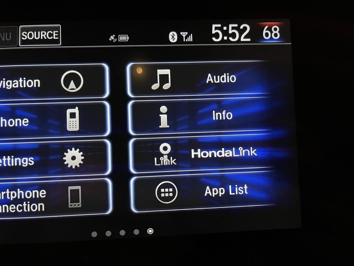 A photo of a car infotainment system showing a "HondaLink" option with a stylized letter "i"