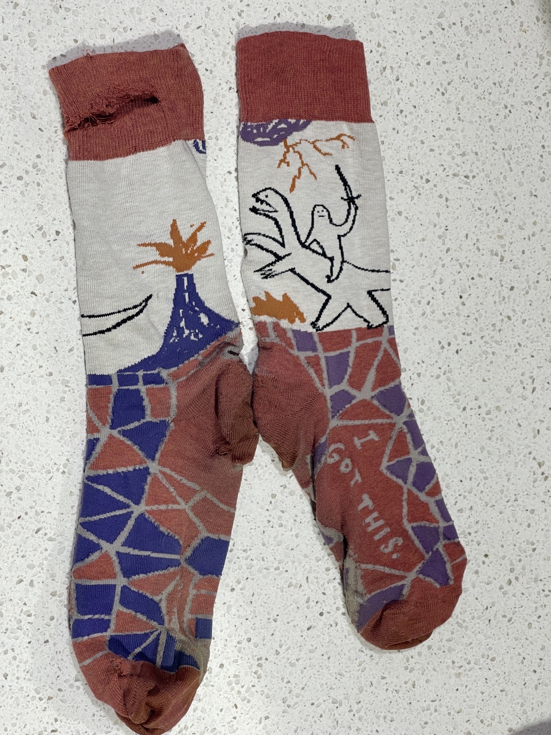 A picture of a pair of worn-out socks, with a picture of a sword-weilding blob riding a dinosaur