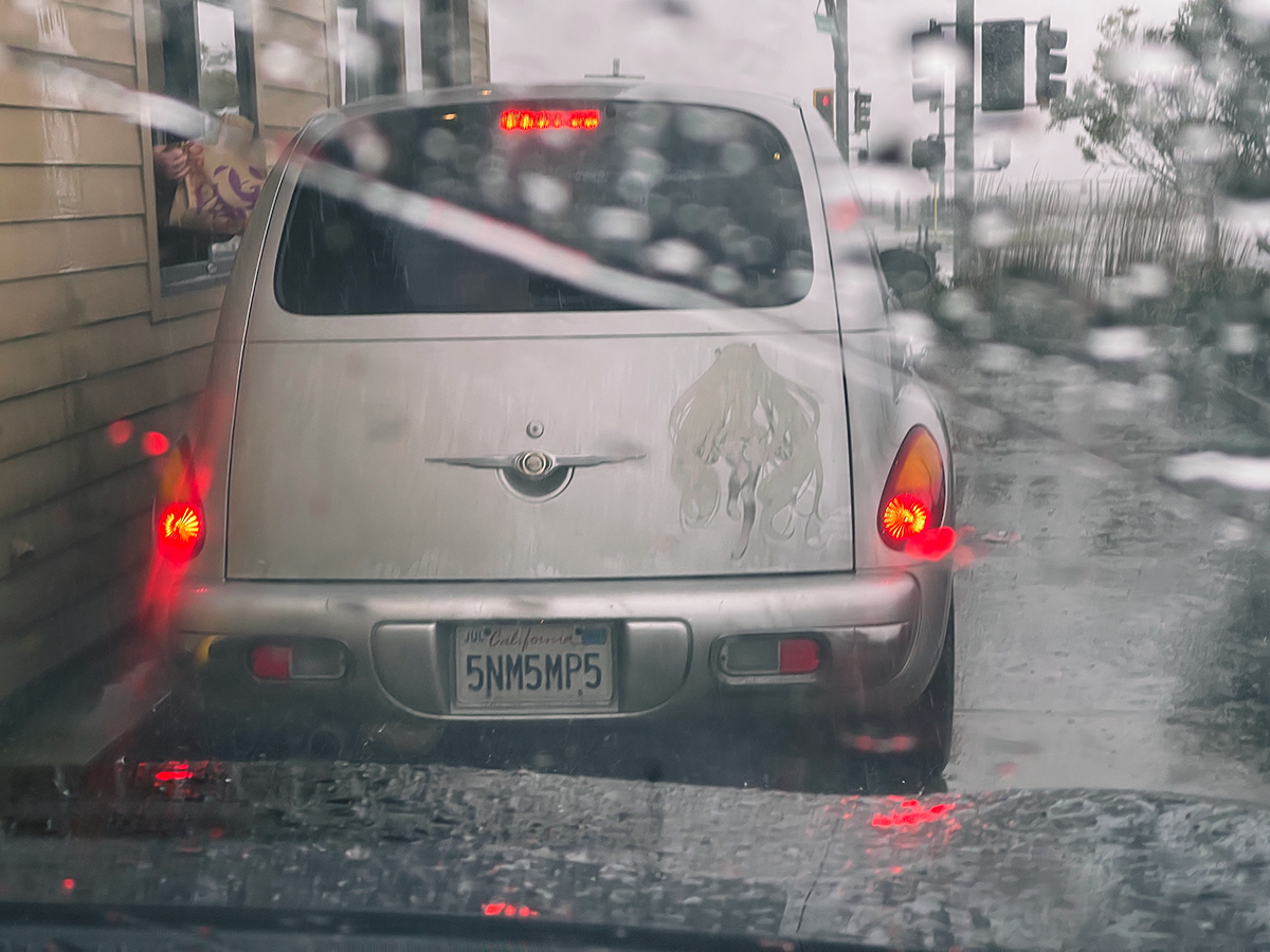 An image of a PT Cruiser at a Taco Bell drive-through in the rain