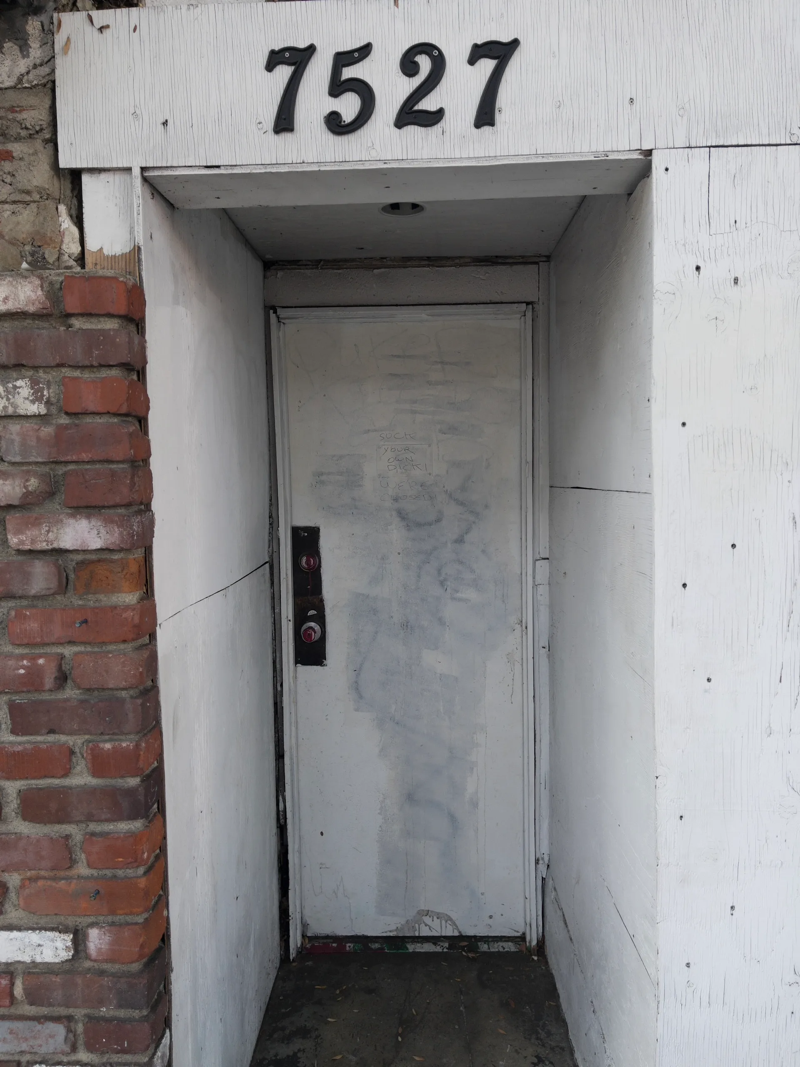 A photo of a cheaply-painted doorway with the street address 7527