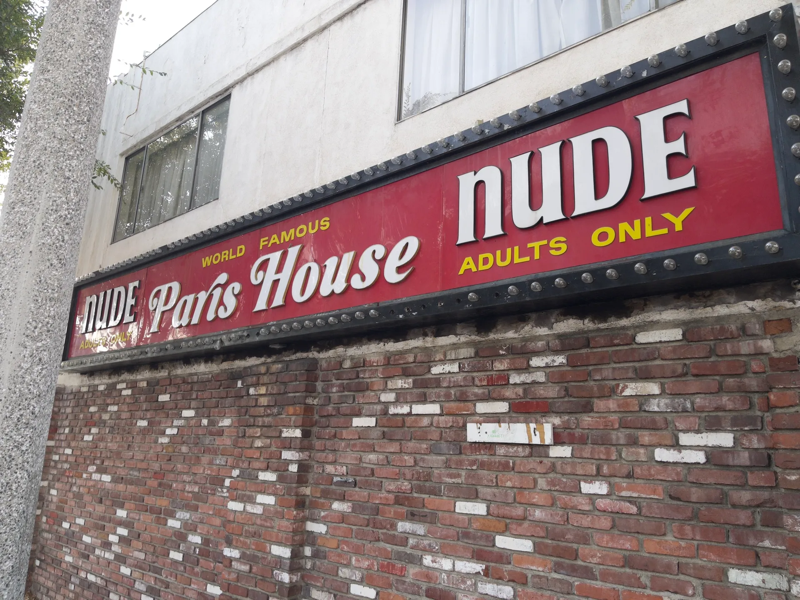 A photo of a building with a red marquee with white letters reading "World Famous Paris House - NUDE - Adults Only"