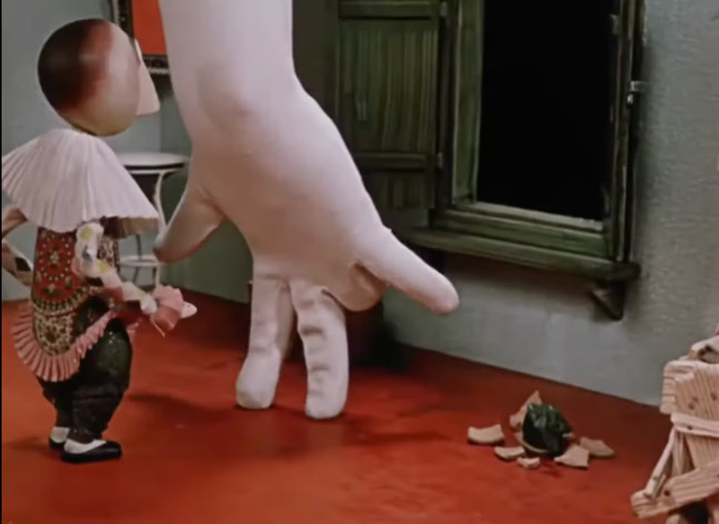 Screenshot_2025-05-04_at_4.49.20_PM.png.png A still from an animated film showing a stop-motion puppet reacting to a white-gloved hand