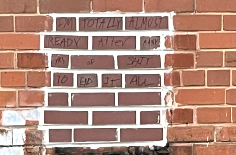 A zoomed in view of the bricks revealing graffiti reading "I'm TOTALLY ALMOST READY AFTER MANY YRS OF SHIT TO END IT ALL"