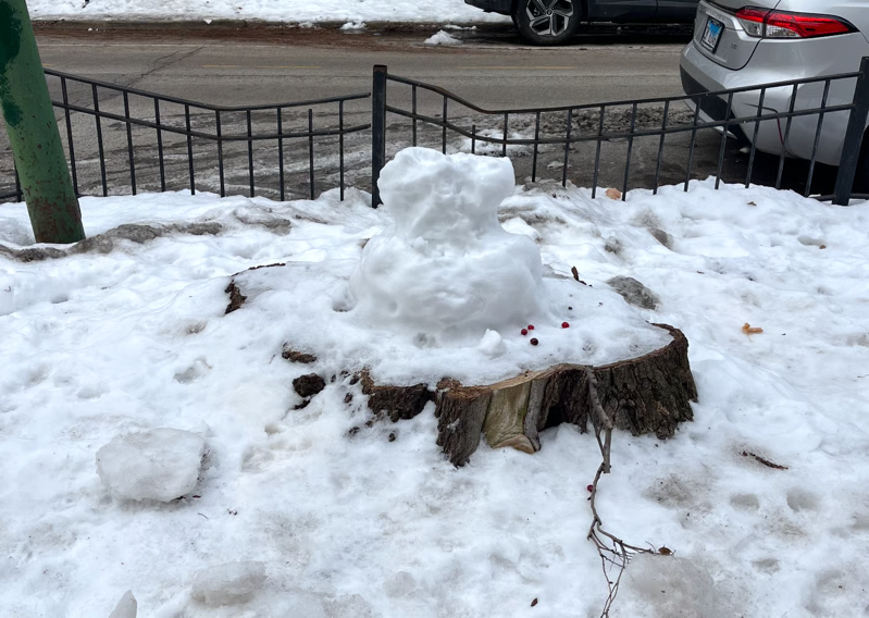 A photo of a stump with the remains of a damaged snowman on it.