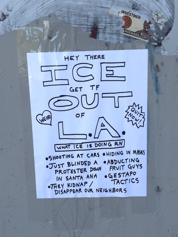 A photo of a poster taped to the side of a wall. It reads "HEY THERE
ICE
GET TF
OUT
OF
LA
WHAT ICE IS DOING RN
• SHOOTING AT CARS • HIDING IN MASKS • JUST BLINDED A • 
PROTESTER DOWN IN SANTA ANA • ABDUCTING FRUIT GUYS • GESTAPO TACTICS •THEY KIDNAP /
DISAPPEAR OUR NEIGHBORS"