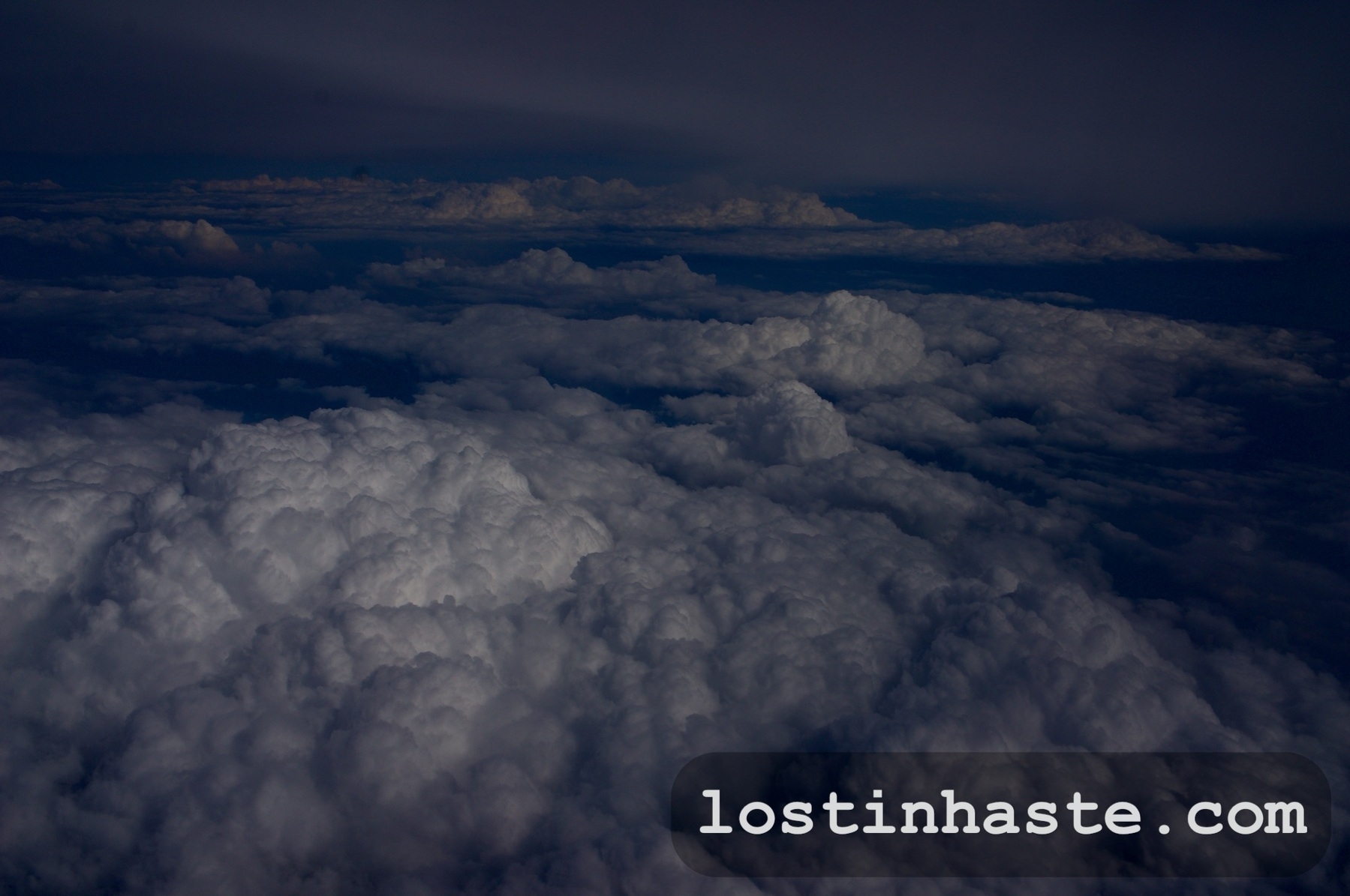 Billowing clouds dominate the view against a dark, moody sky. The website 'lostinthehaste.com' overlays at the bottom.