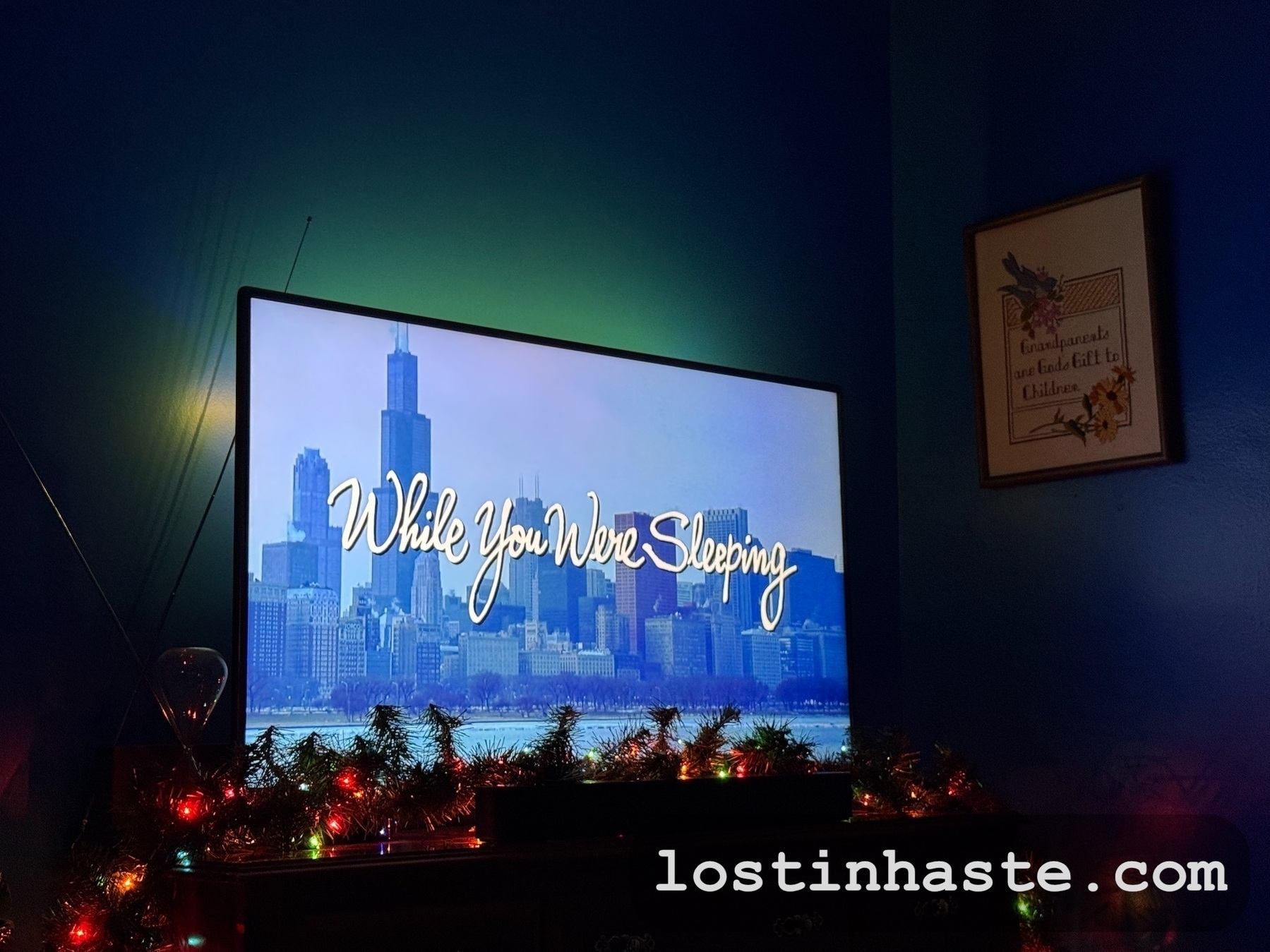 Auto-generated description: A television screen displays the title While You Were Sleeping with a cityscape background, surrounded by holiday decorations.