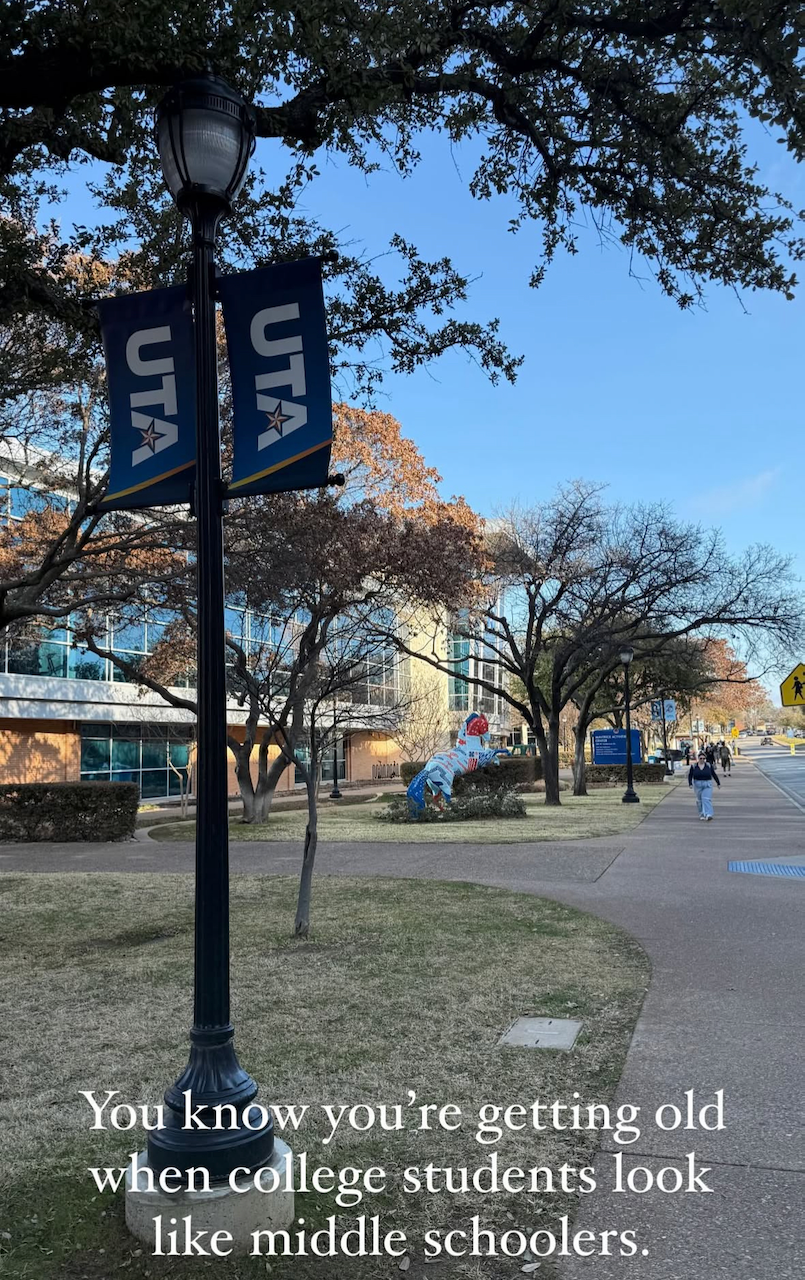 A campus walkway is lined with trees and flags bearing the 'UTA' logo, featuring a humorous caption about aging and college students.