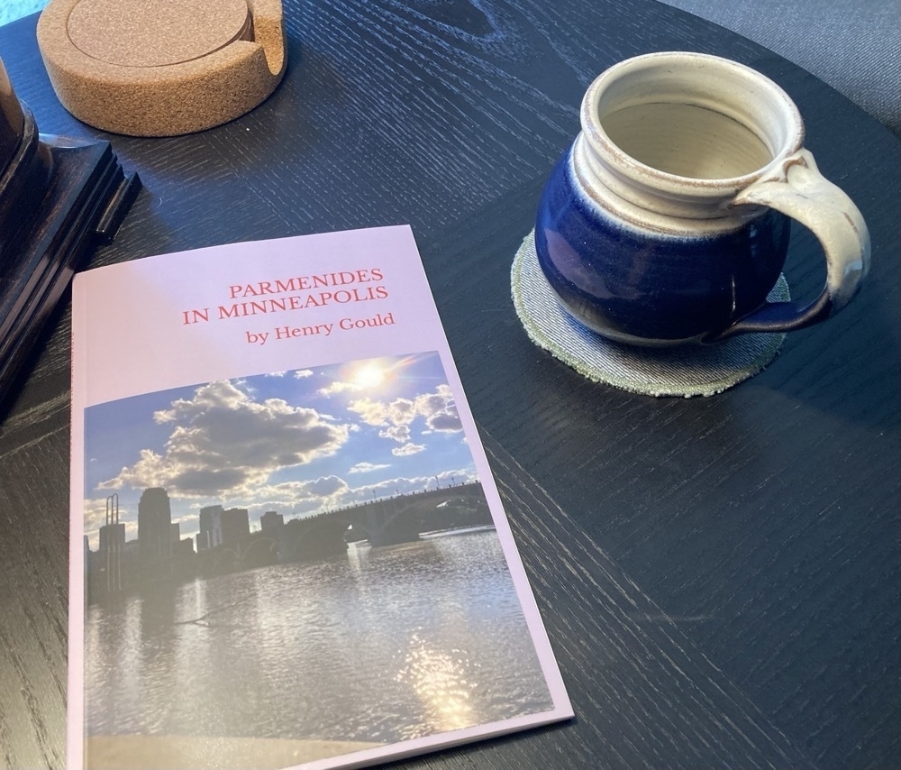 Henry Gould's chapbook, Parmenides in Minneapolis, lying on a table, with a small cobalt-blue mug neaby