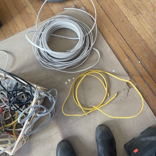 Electrical wiring on the floor and in a milk crate.