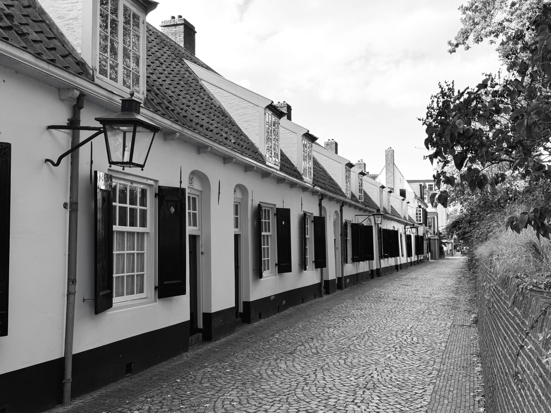 Black and white photo of a street where the repeated windows, roofs and the street leads you view from left to right